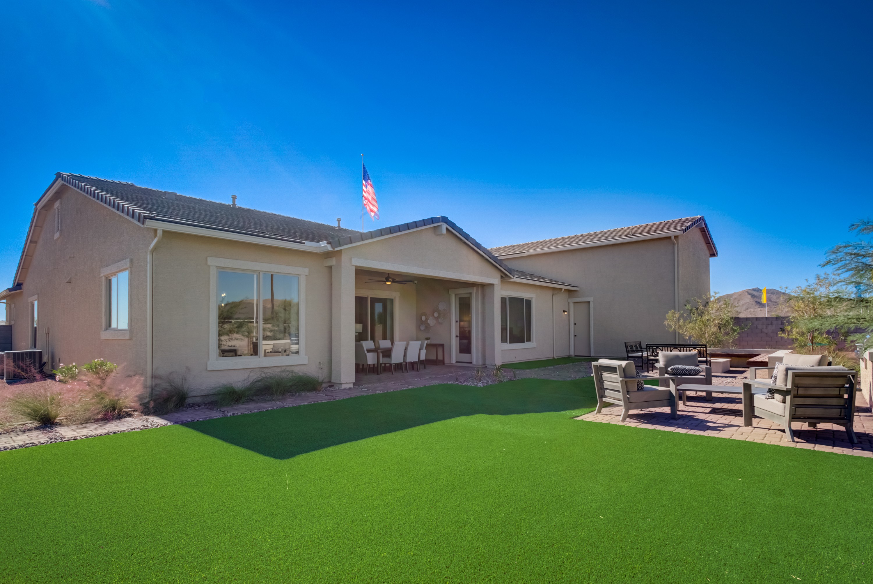 Luxury Home with Patio and Lawn in Arroyo Seco, Palazzo Community Single-story home in Arroyo Seco, Palazzo. Features large windows, patio, manicured lawn, and outdoor seating.