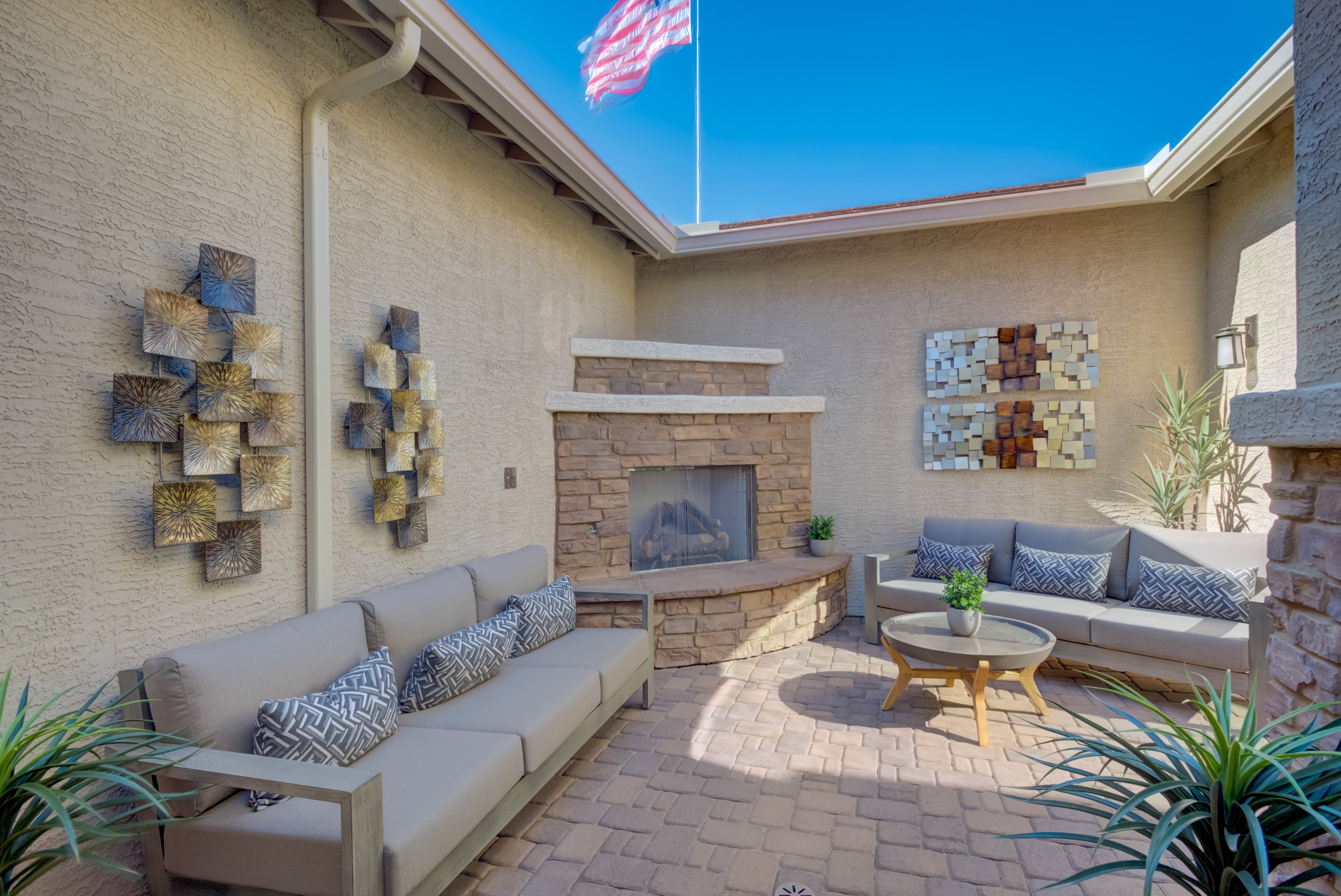 Luxury Patio with Stone Fireplace at Arroyo Seco Palazzo Community Luxury patio with stone fireplace, elegant metal wall art, plush seating, and pavers at Arroyo Seco - Palazzo community.