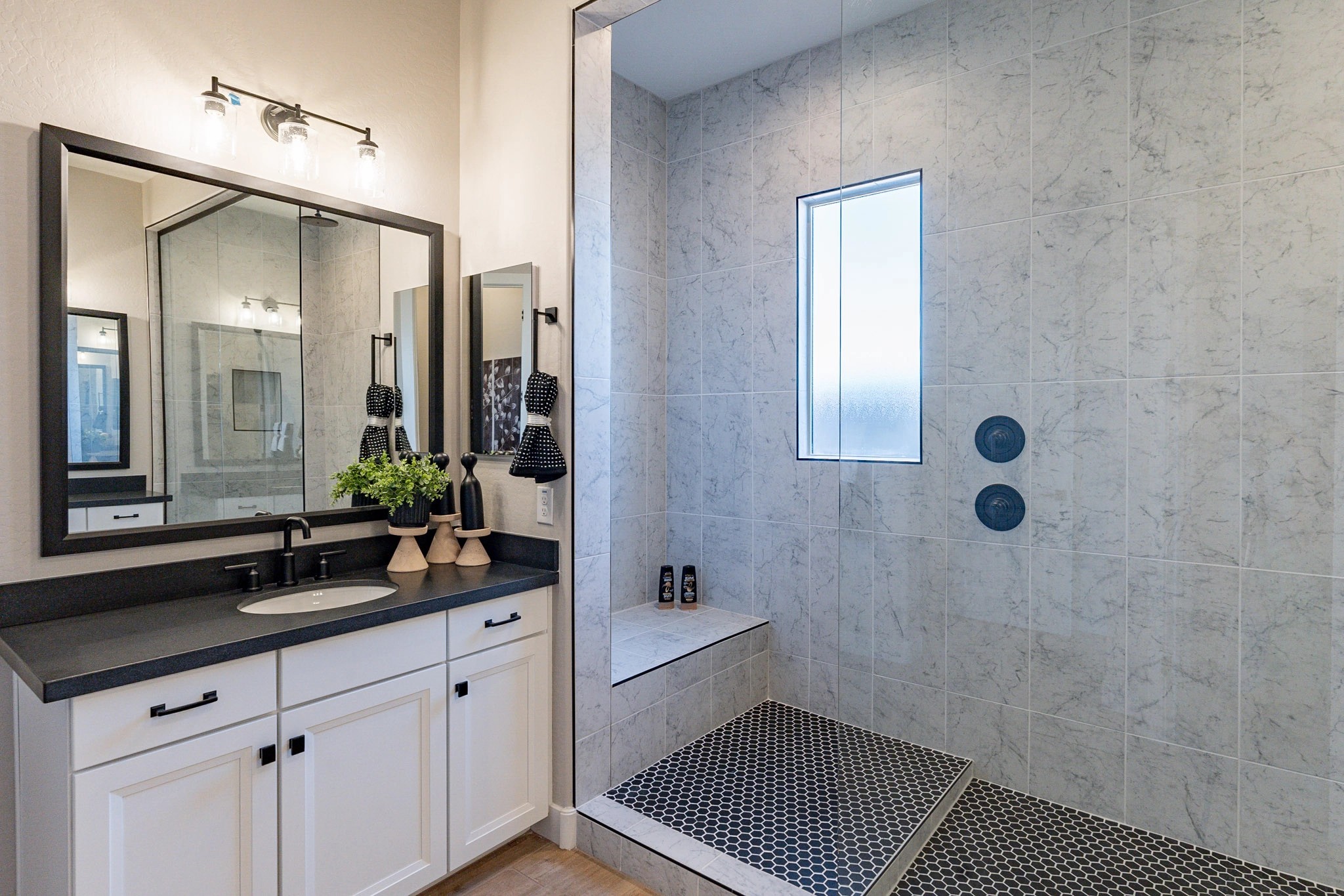 Luxurious Bathroom Design in Arroyo Seco Hacienda Community Modern bathroom with marble tiles, glass shower, black countertop, double vanity in Arroyo Seco Hacienda.