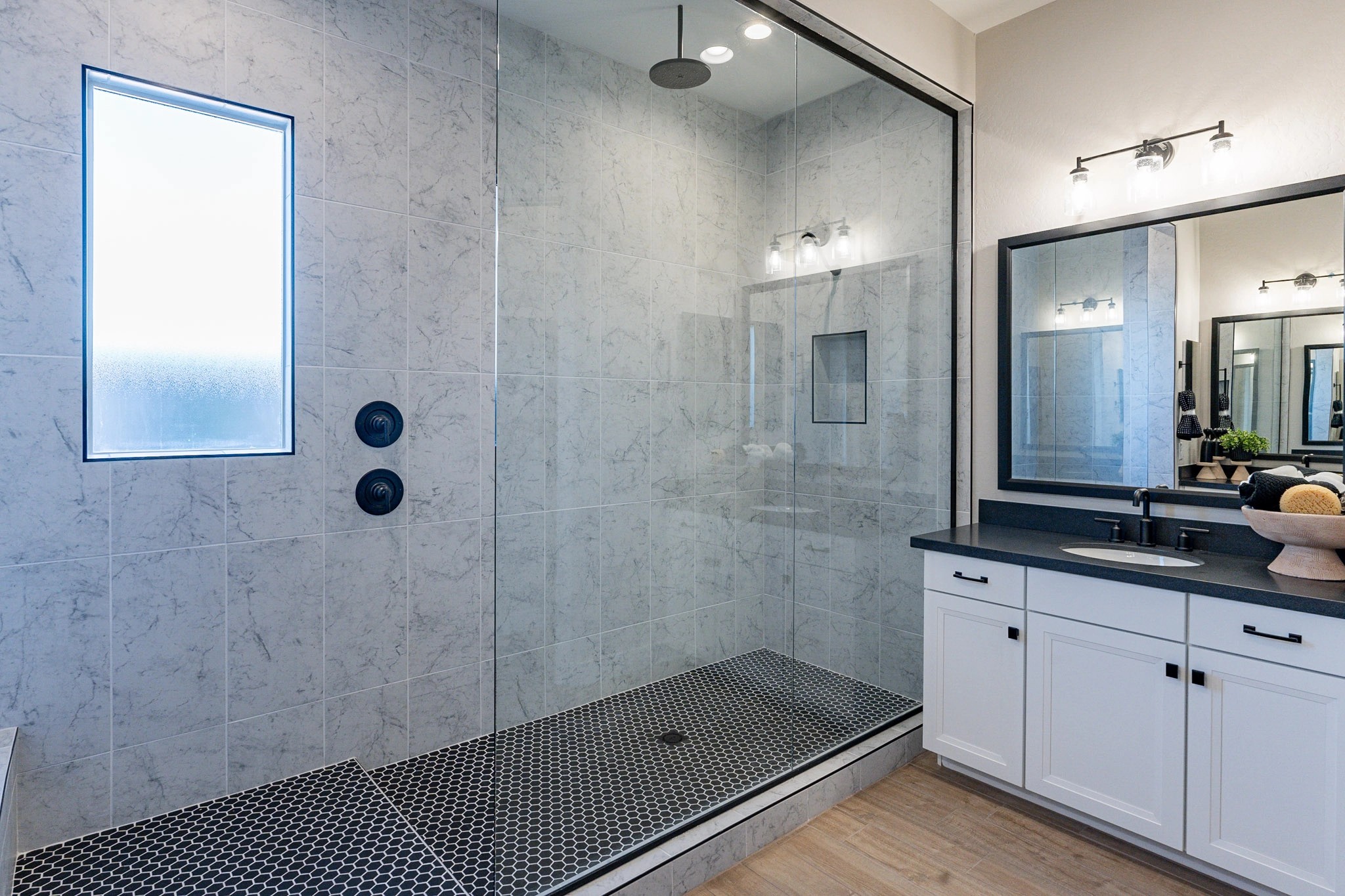 Luxury Bathroom with Glass Shower in Arroyo Seco Hacienda Elegant bathroom in Arroyo Seco with glass shower, marble tiles, modern lighting, black fixtures.