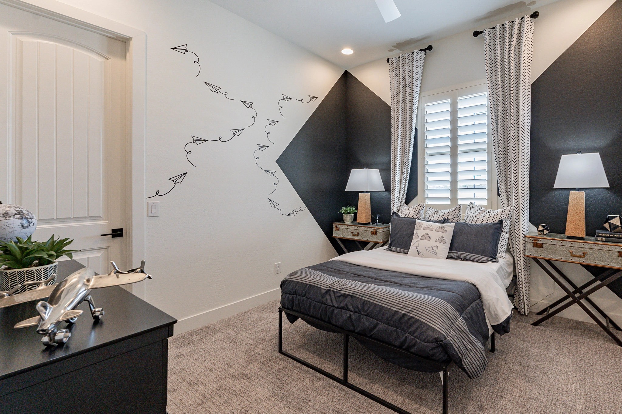 Luxurious Bedroom Design in Arroyo Seco Hacienda Community Modern bedroom with black accents, paper plane wall art, dual nightstands, in Arroyo Seco Hacienda community.