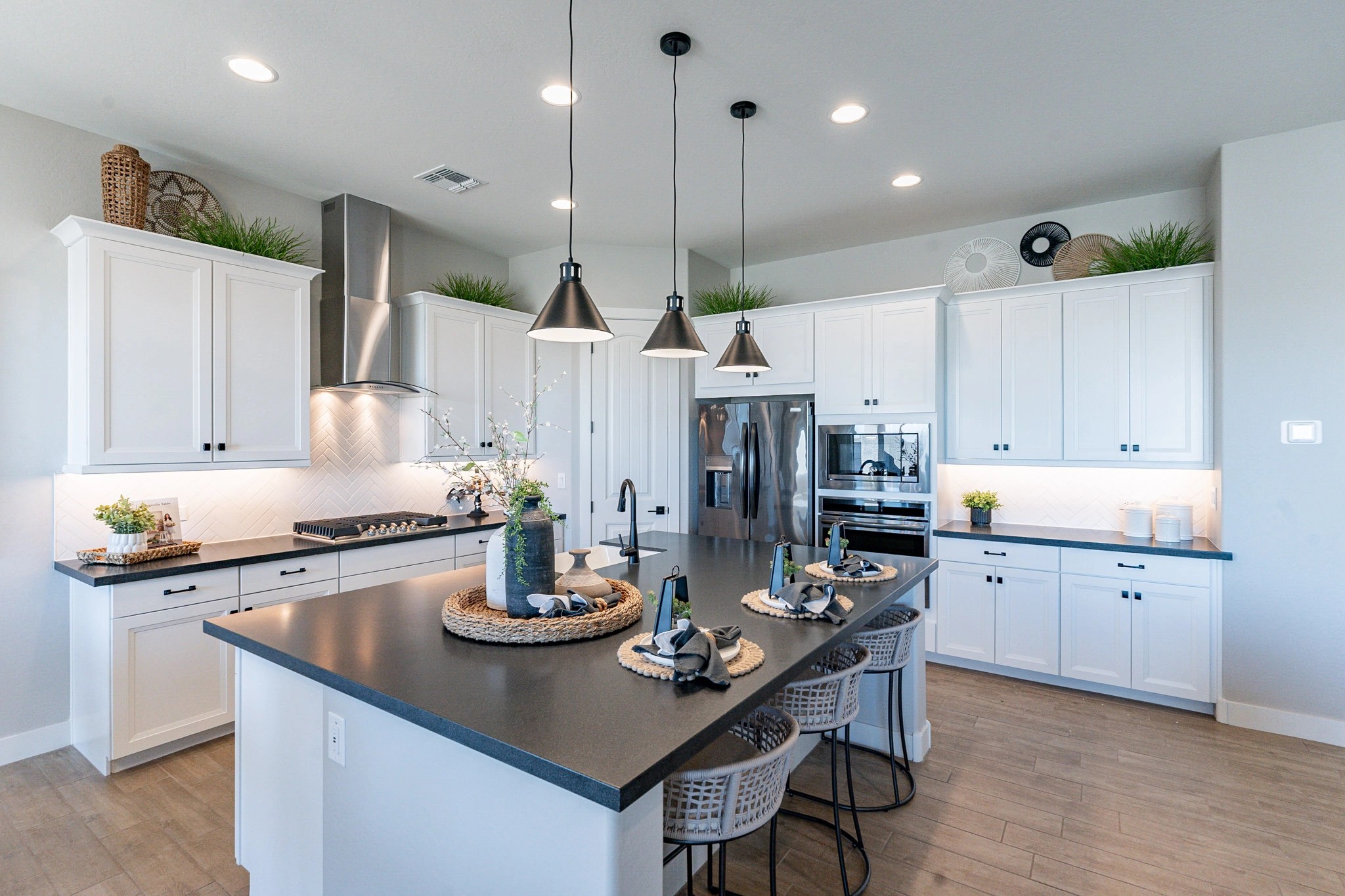 Arroyo Seco Hacienda Kitchen with White Cabinets and Pendant Lighting Modern kitchen with white cabinets, dark countertops, pendant lights, and bar seating in Arroyo Seco, Hacienda community.