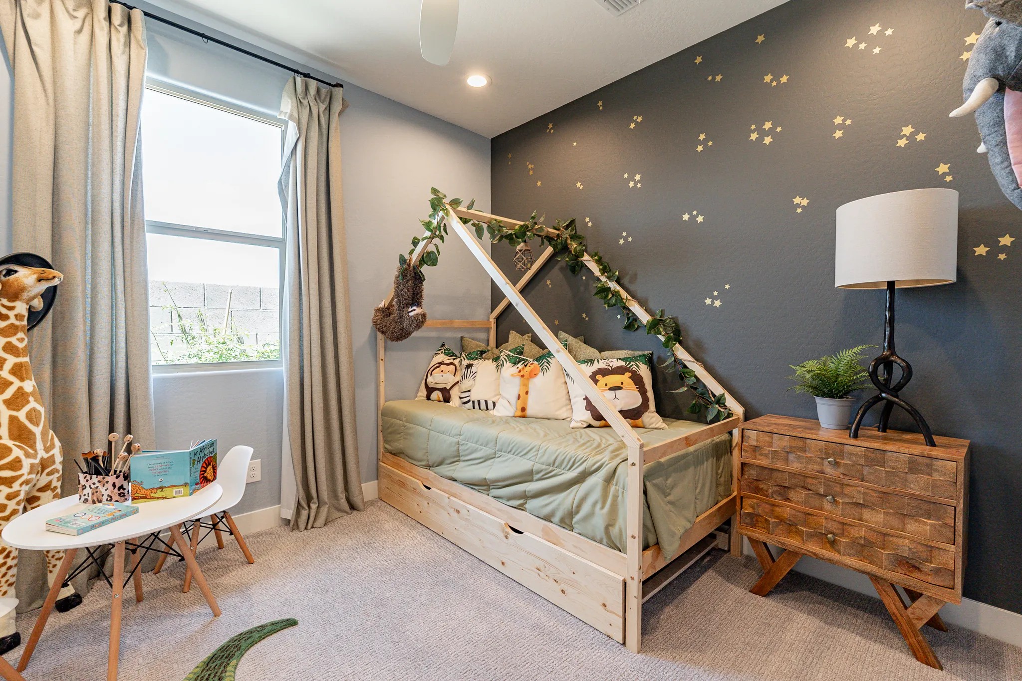 Child's Room with Unique House Bed in Sienna Park Child's room with house-shaped bed, animal pillows, and nature decor, Sienna Park community. Gray walls, charming lighting.