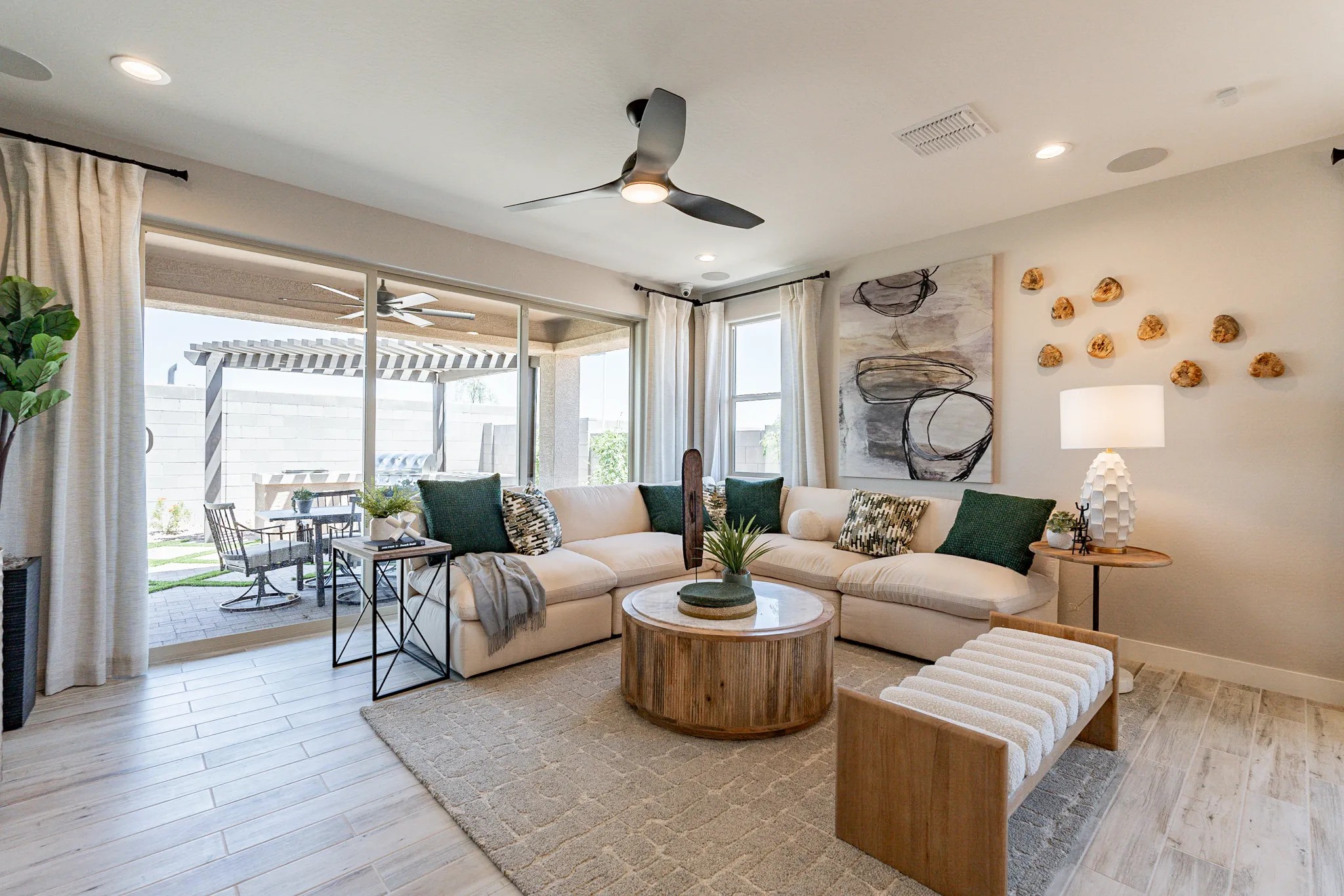 Modern Living Room Design in Sienna Park with Patio View Modern living room with large sectional, wood accents, abstract art, Sienna Park. Patio and pergola visible.