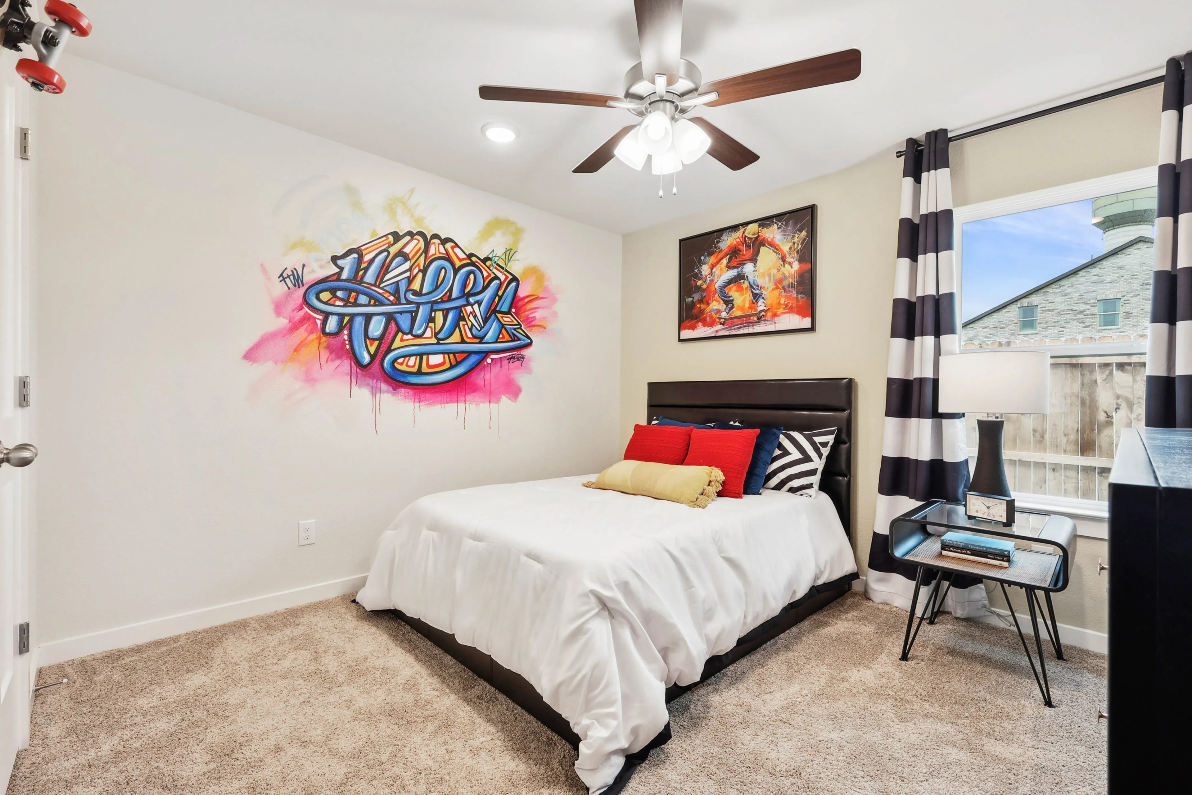 Modern Bedroom with Graffiti Art in Simpson Crossing Bedroom with graffiti art, ceiling fan, striped curtains, modern decor in Simpson Crossing, cozy carpet flooring.