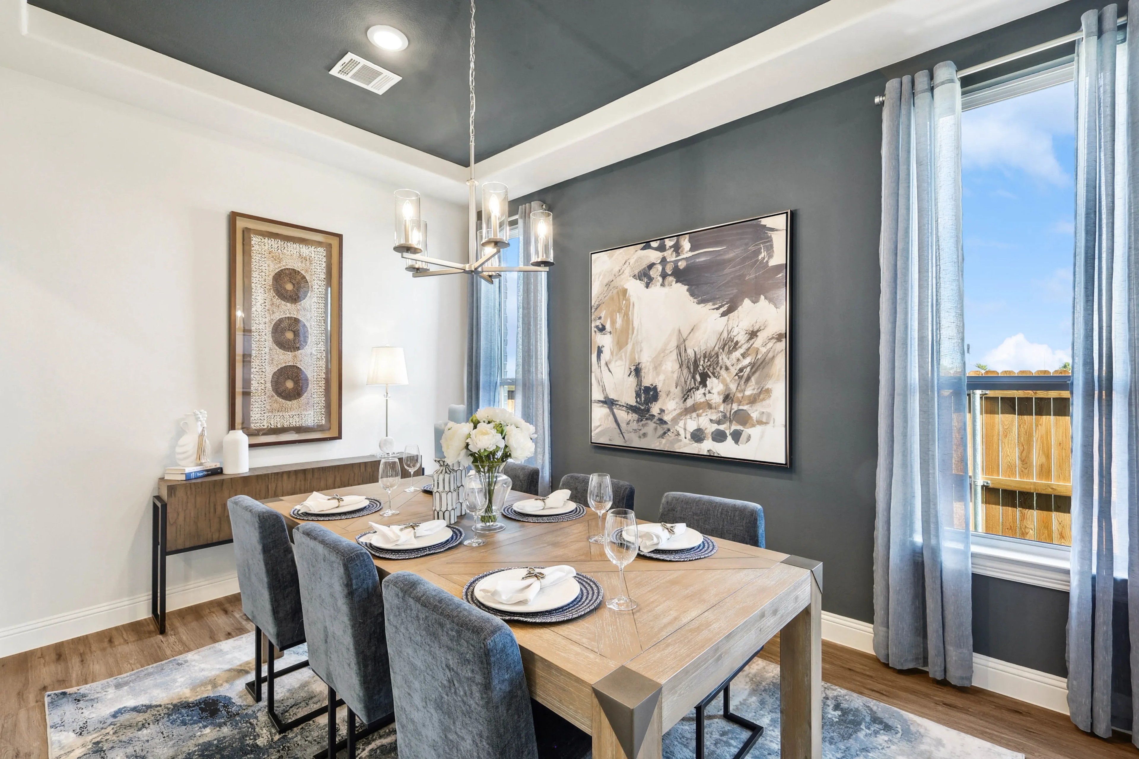 Ridge Crossing Dining Room with Modern Art and Elegant Decor Elegant dining room with abstract art, wooden table, velvet chairs, chandelier, located in Ridge Crossing community.