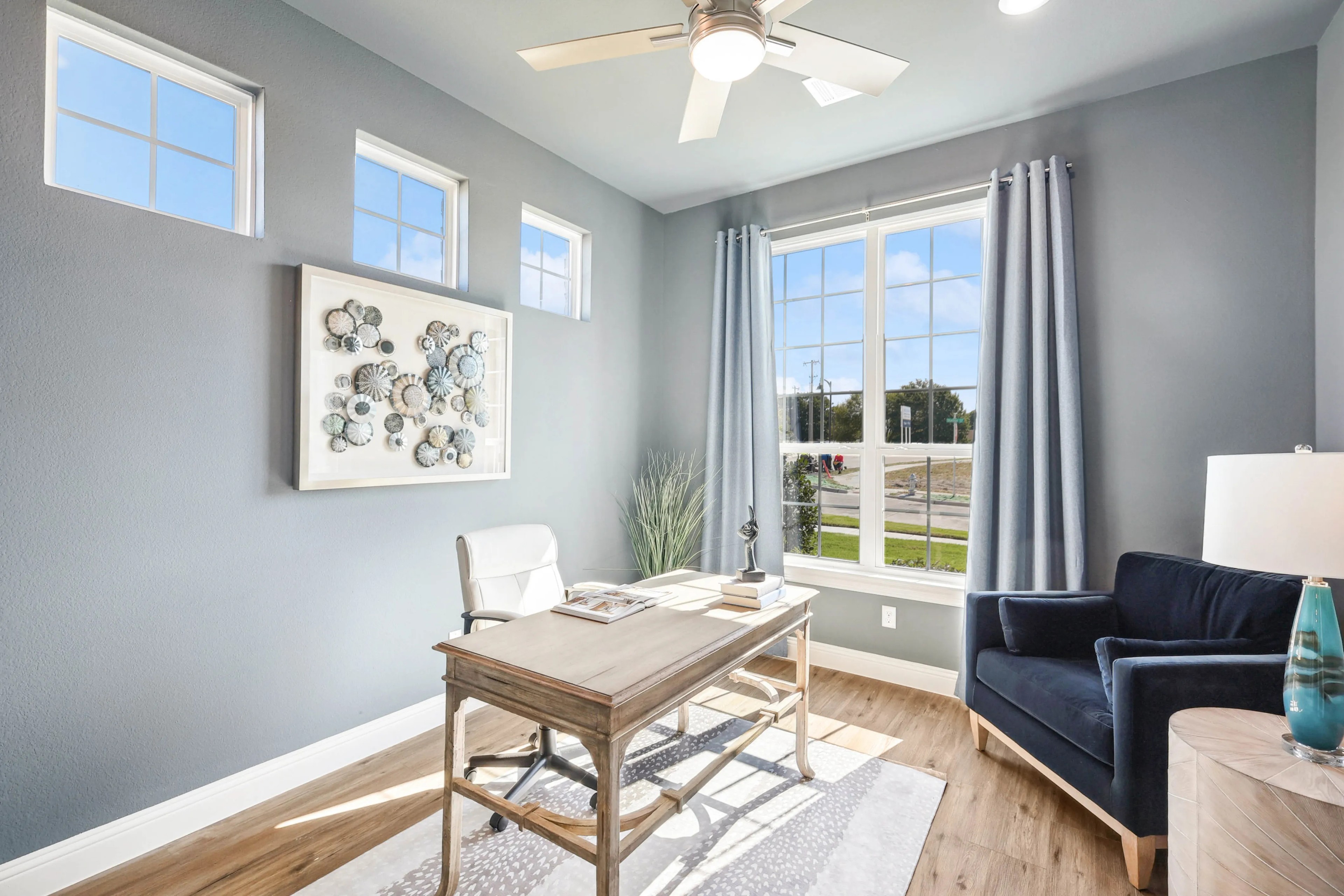 Modern Home Office Design in Ridge Crossing Community Elegant home office with large windows, modern ceiling fan, and stylish decor in Ridge Crossing community.