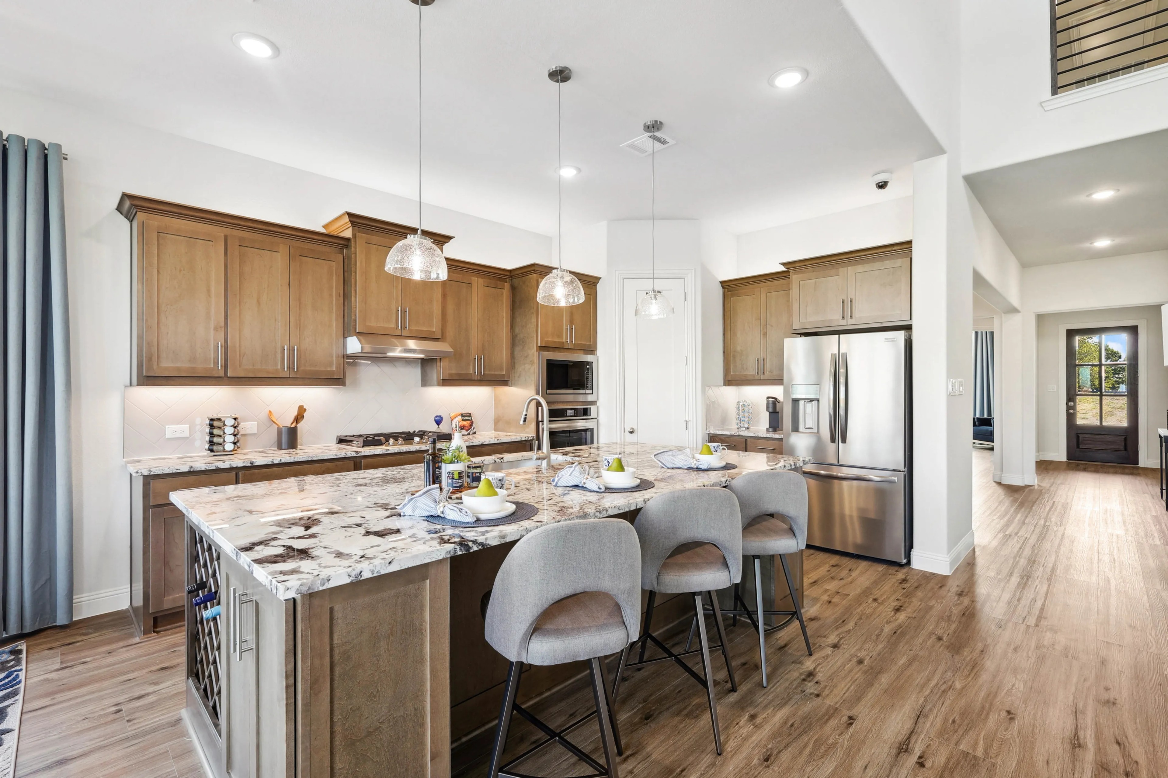 Ridge Crossing Kitchen with Marble Island and Wood Cabinets Modern kitchen in Ridge Crossing with wooden cabinets, marble island, stainless steel appliances, pendant lights.