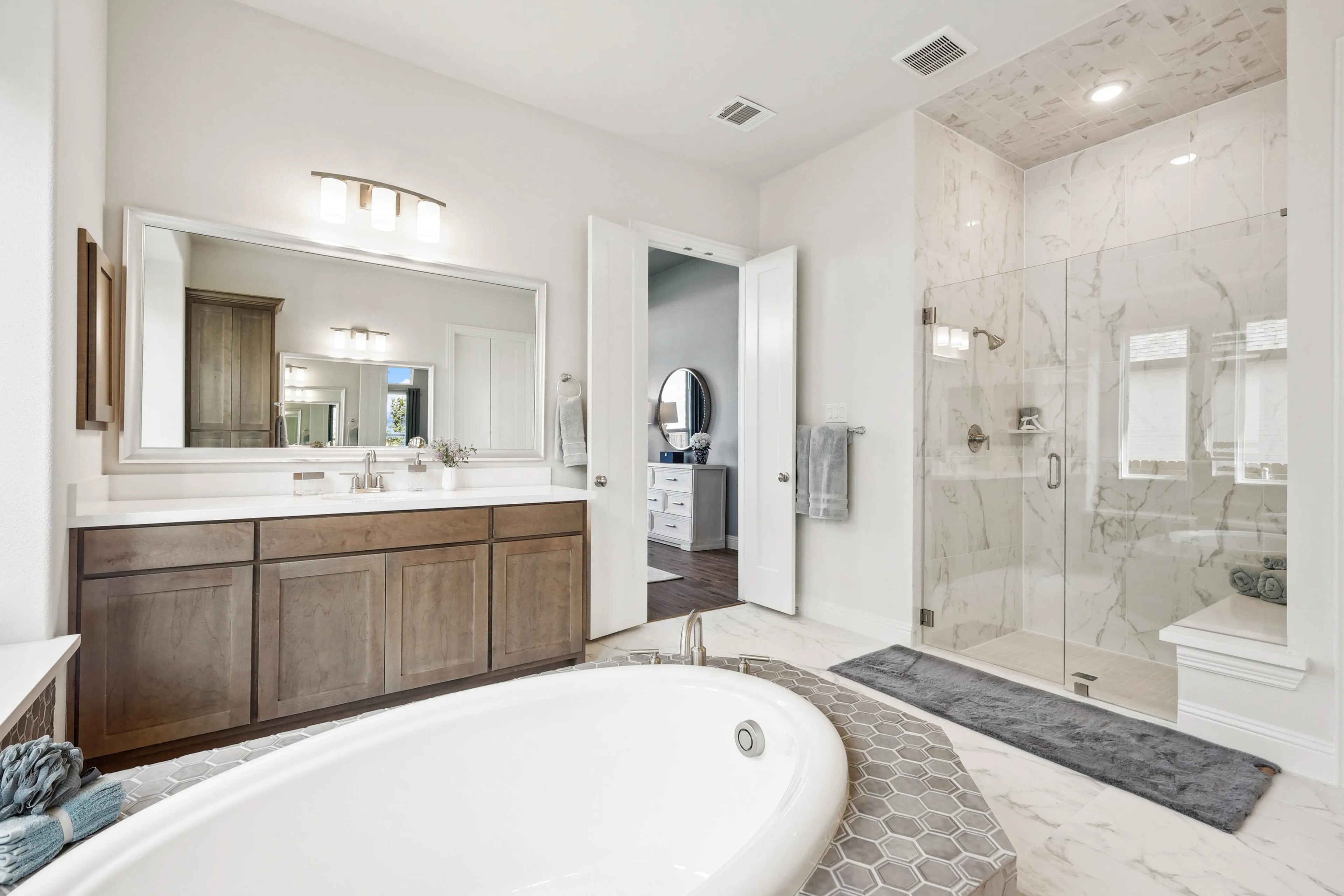 Elegant Marble Bathroom at Ridge Crossing Community Luxurious bathroom with marble shower, freestanding tub, and wooden vanity in Ridge Crossing community.
