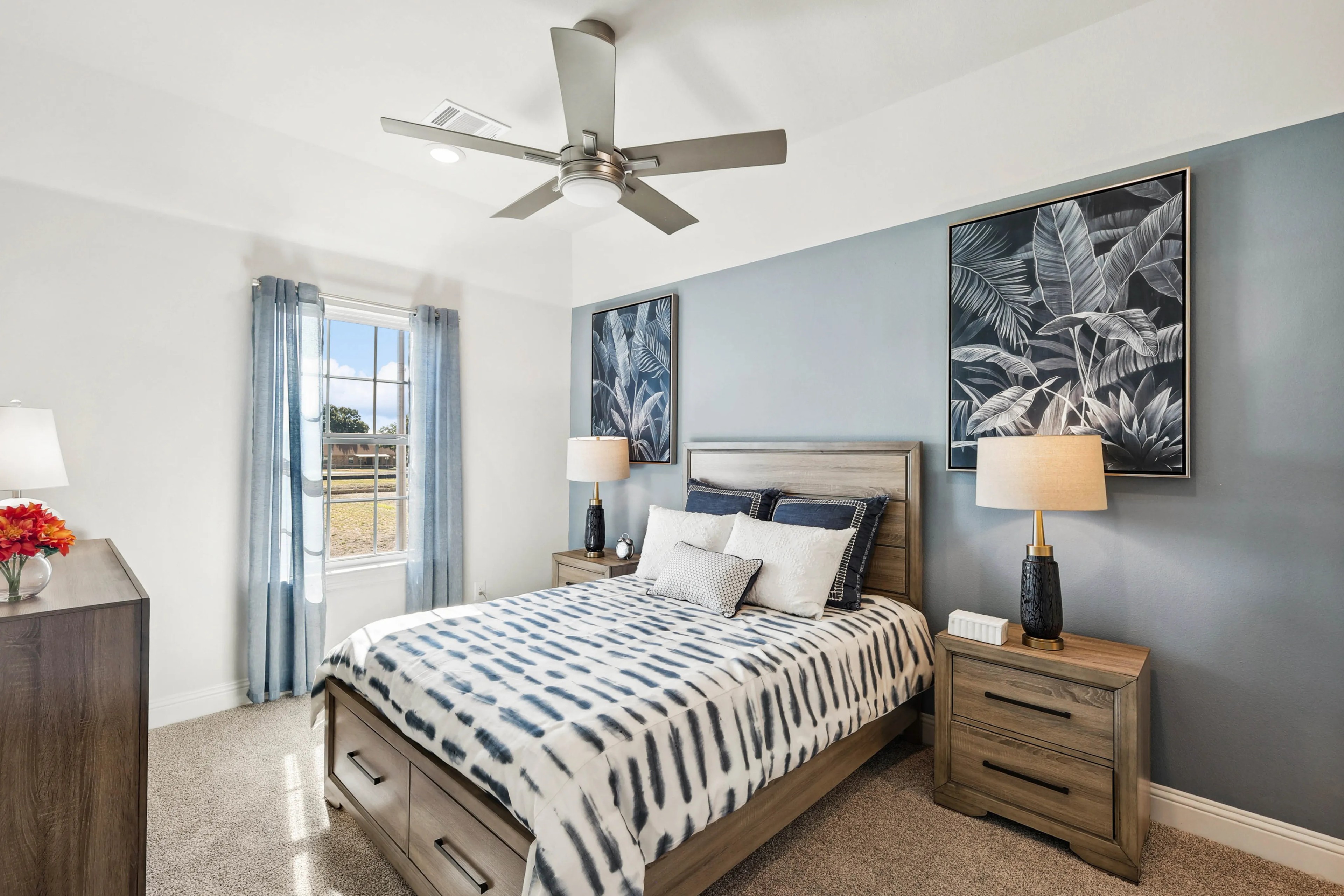 Luxurious Bedroom Design in Ridge Crossing Stylish Ridge Crossing bedroom with modern decor, large window, wooden furniture, blue accents, ceiling fan.