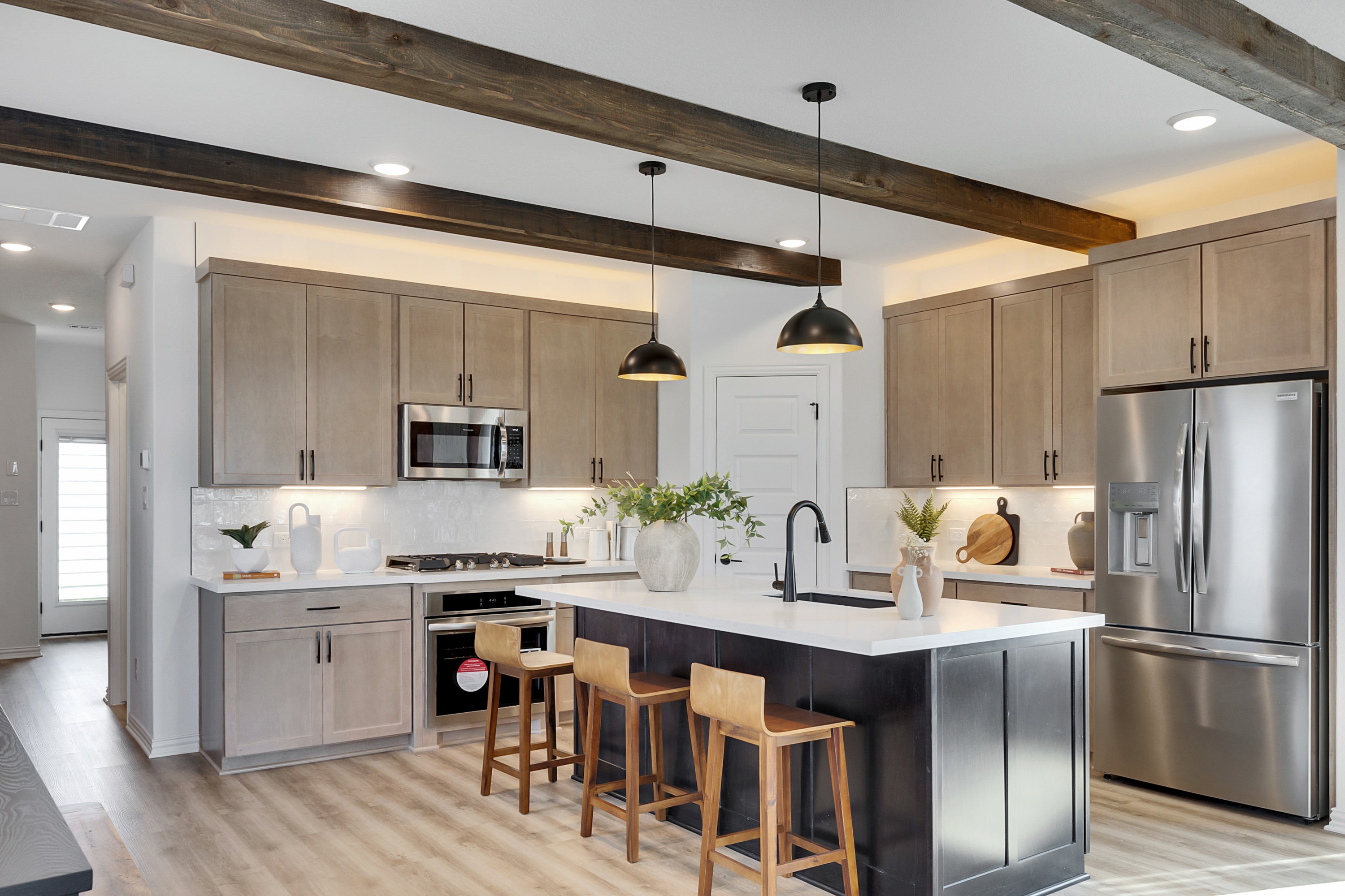 Elegant Modern Kitchen with Island and Appliances in Spring Creek Modern kitchen with light wood cabinetry, large island, pendant lights, steel appliances, Spring Creek.