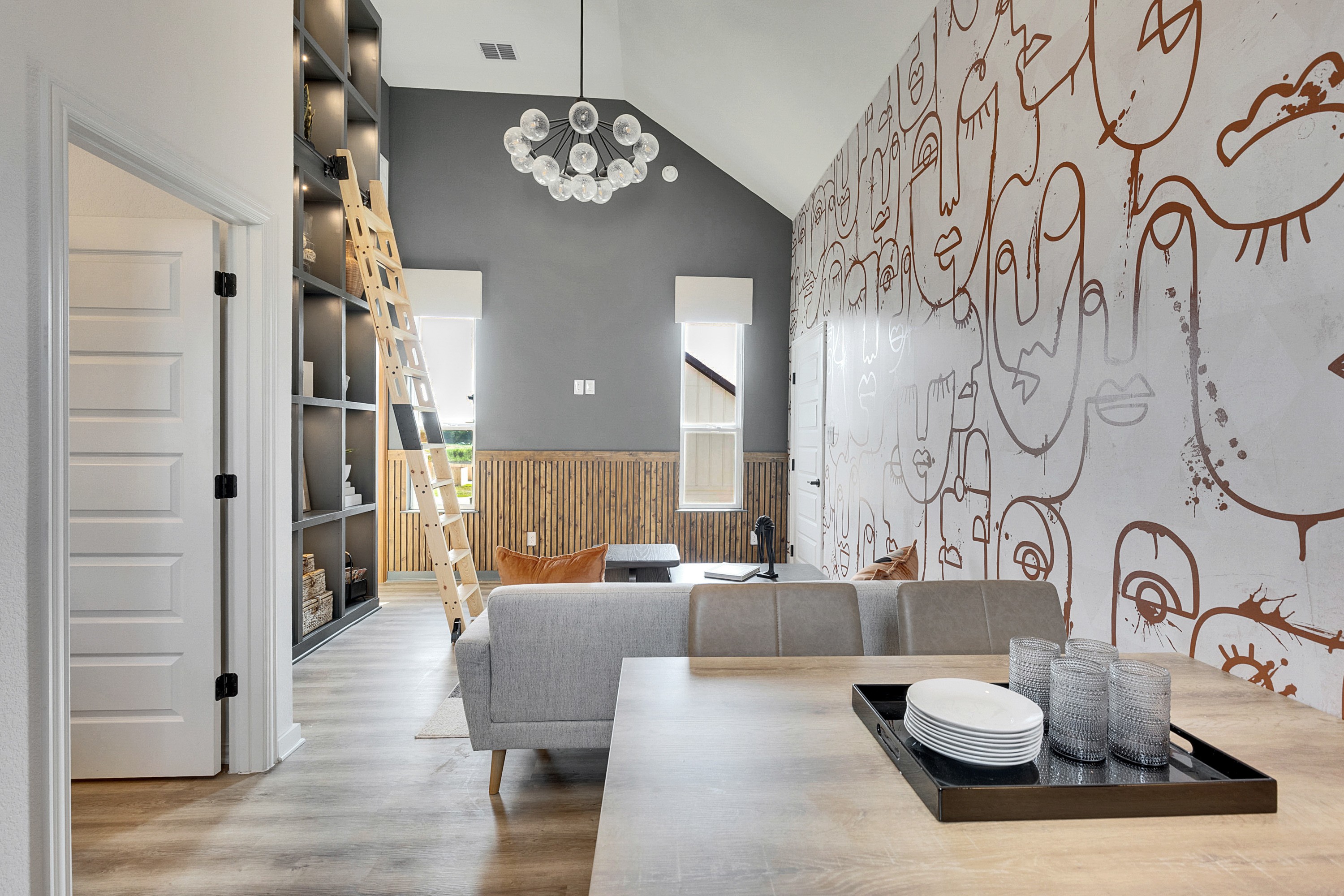 Modern Living Room with Abstract Mural and High Ceilings in Spring Creek Modern living room with abstract mural, high ceilings, custom shelving, and a statement chandelier in Spring Creek.