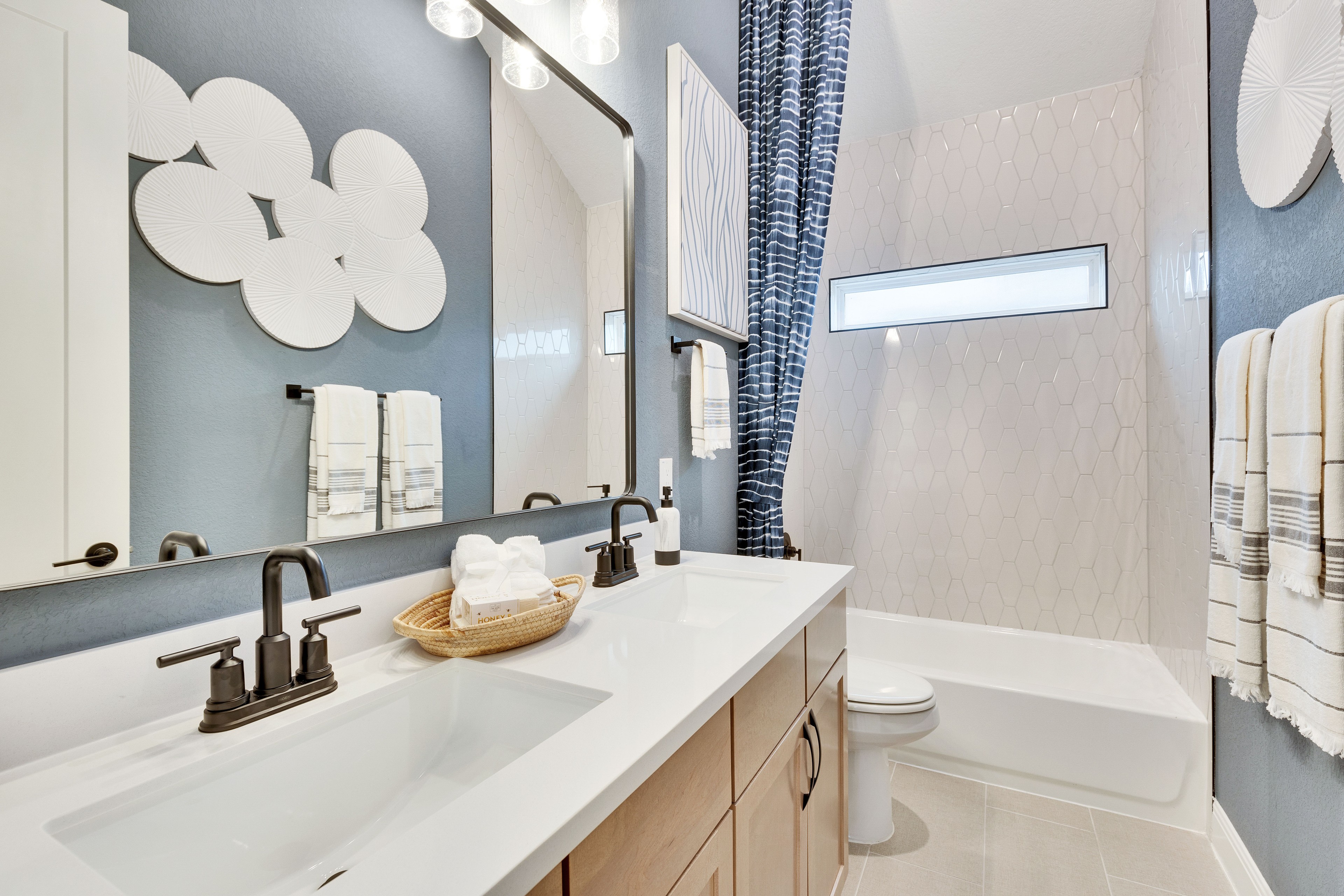 Modern Bathroom with Luxury Fixtures in Spring Creek Modern bathroom with hexagonal tile wall, elegant fixtures, window, art decor, and double vanity in Spring Creek.