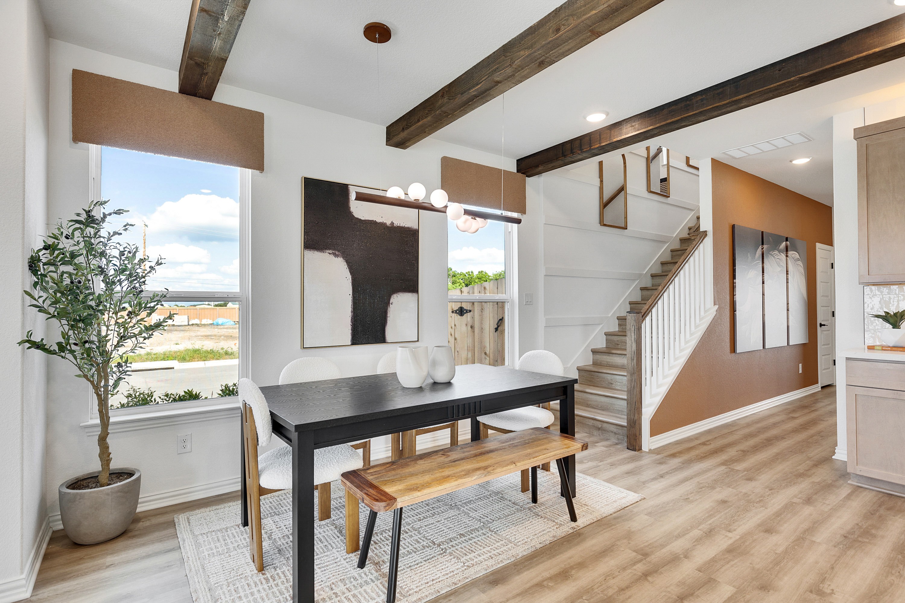 Spring Creek Modern Dining Room with Exposed Wood Beams Modern dining room, Spring Creek, featuring exposed beams, wood flooring, and staircase with artwork.