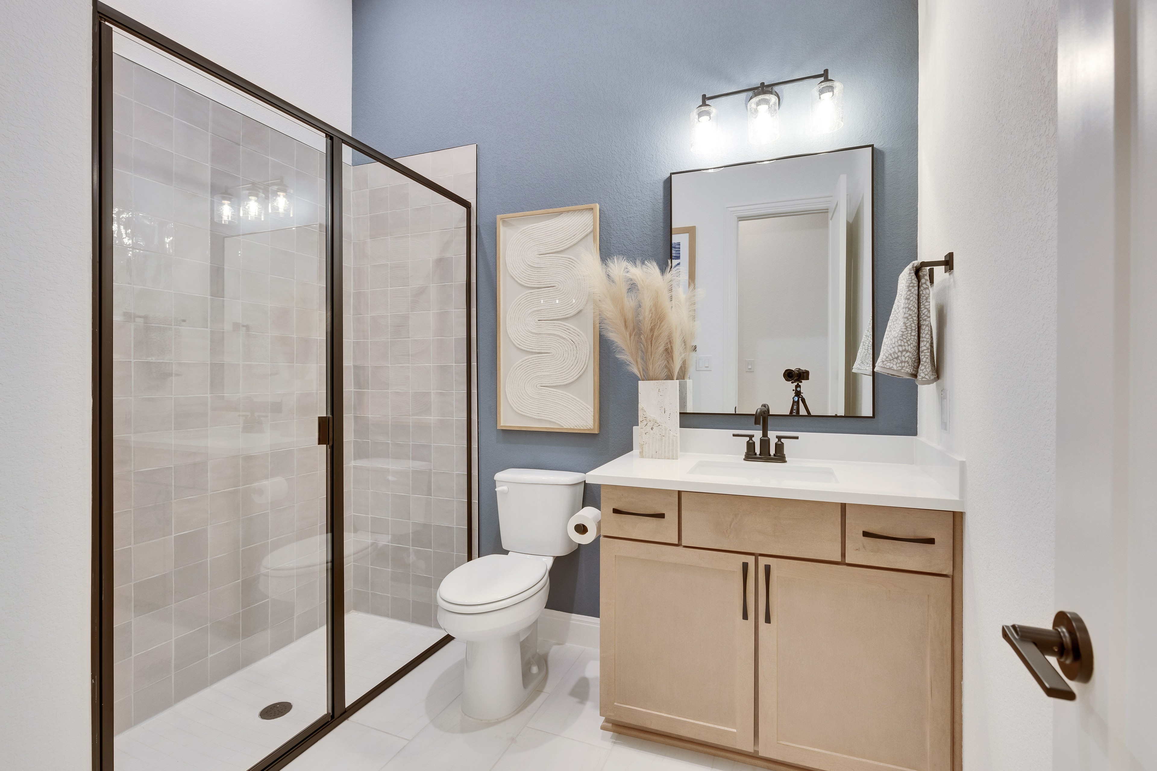Spring Creek Modern Bathroom with Glass Shower and Vanity Modern Spring Creek bathroom with glass shower, sleek vanity, framed art, and large mirror.