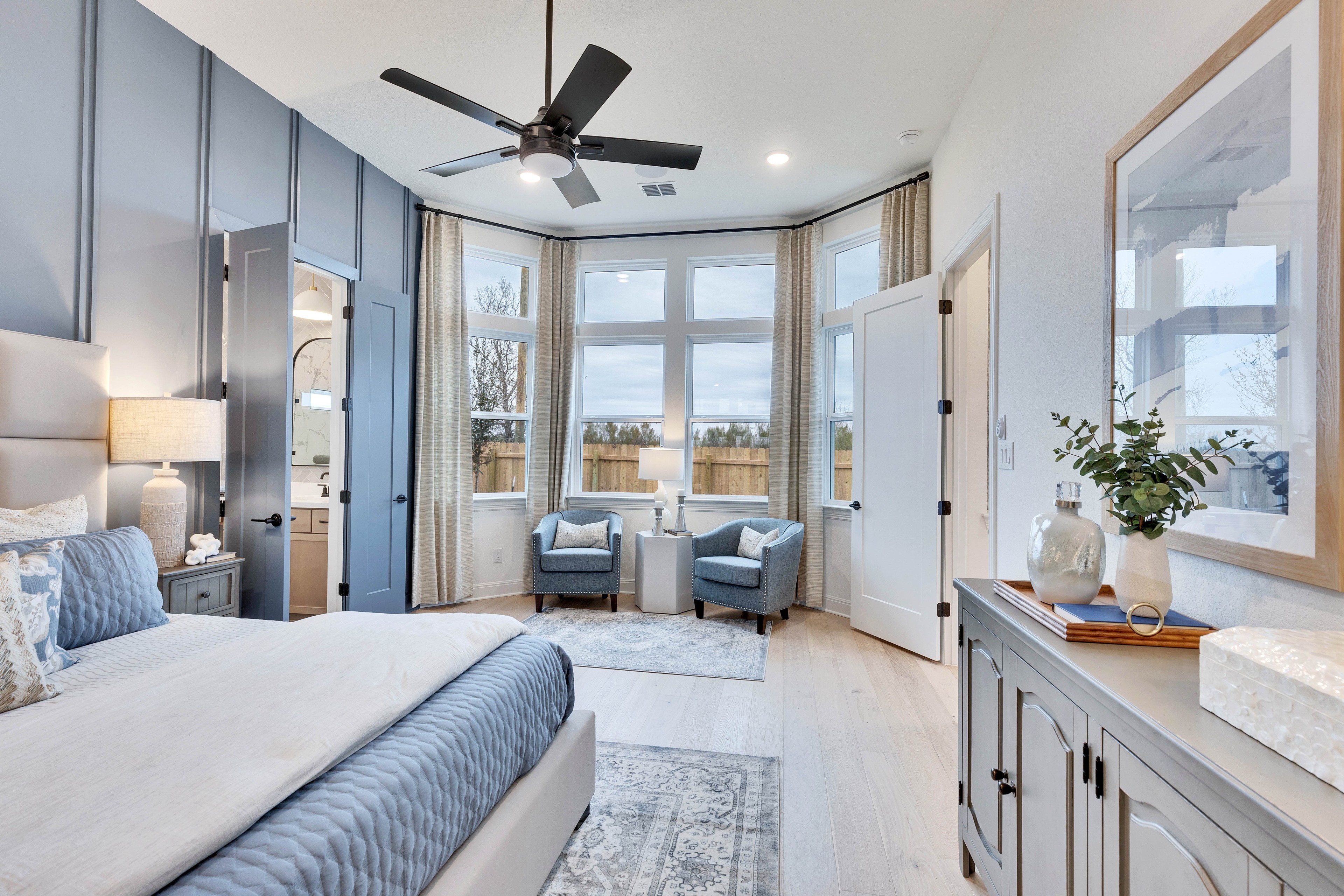 Luxurious Bedroom with Elegant Bay Windows in Spring Creek, Texas Elegant bedroom with large bay windows, soft blue decor, in Spring Creek community, Texas.