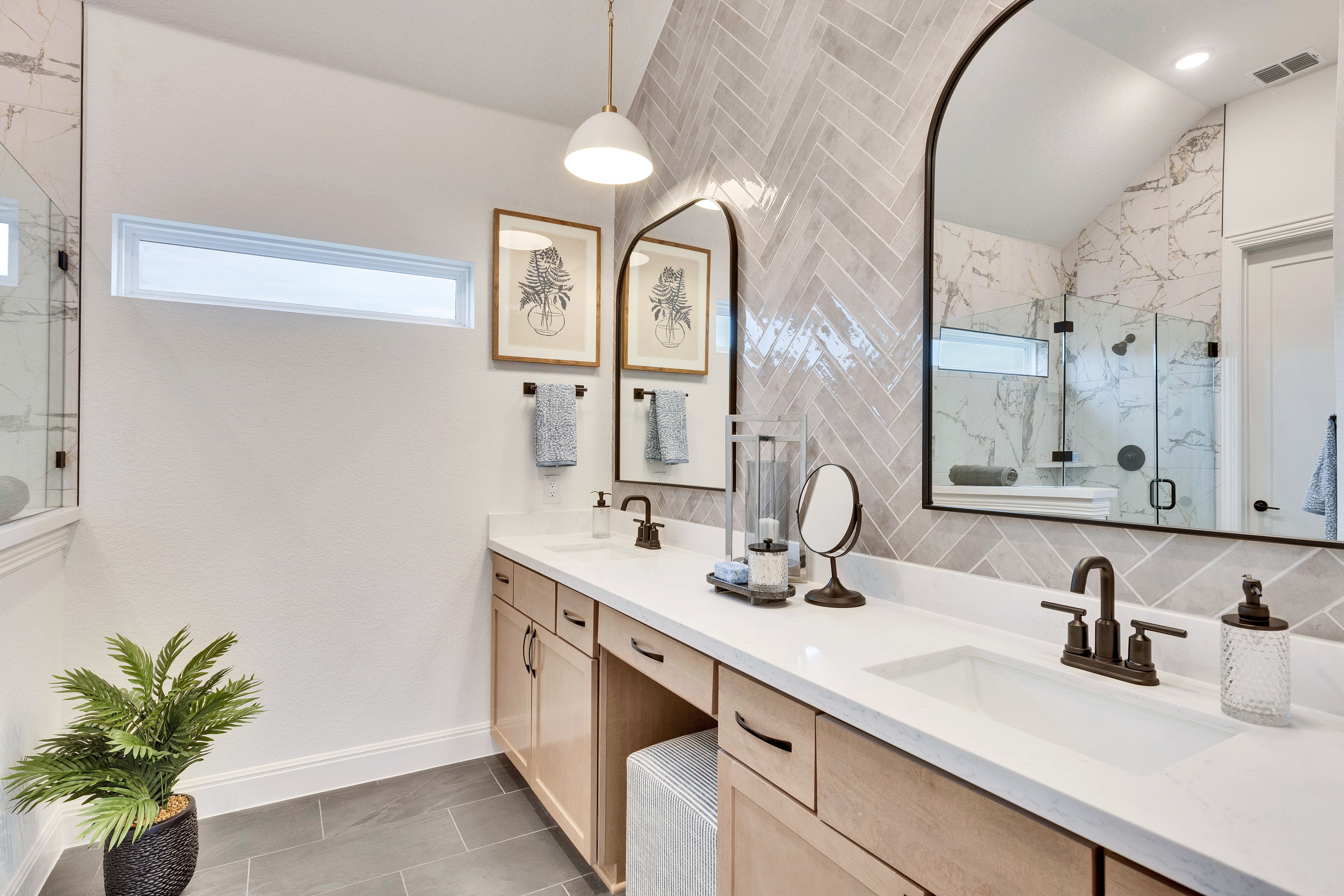 Elegant Spring Creek Bathroom with Dual Sinks and Herringbone Tiles Modern bathroom in Spring Creek with dual sinks, brass fixtures, herringbone tiles, and marble shower.