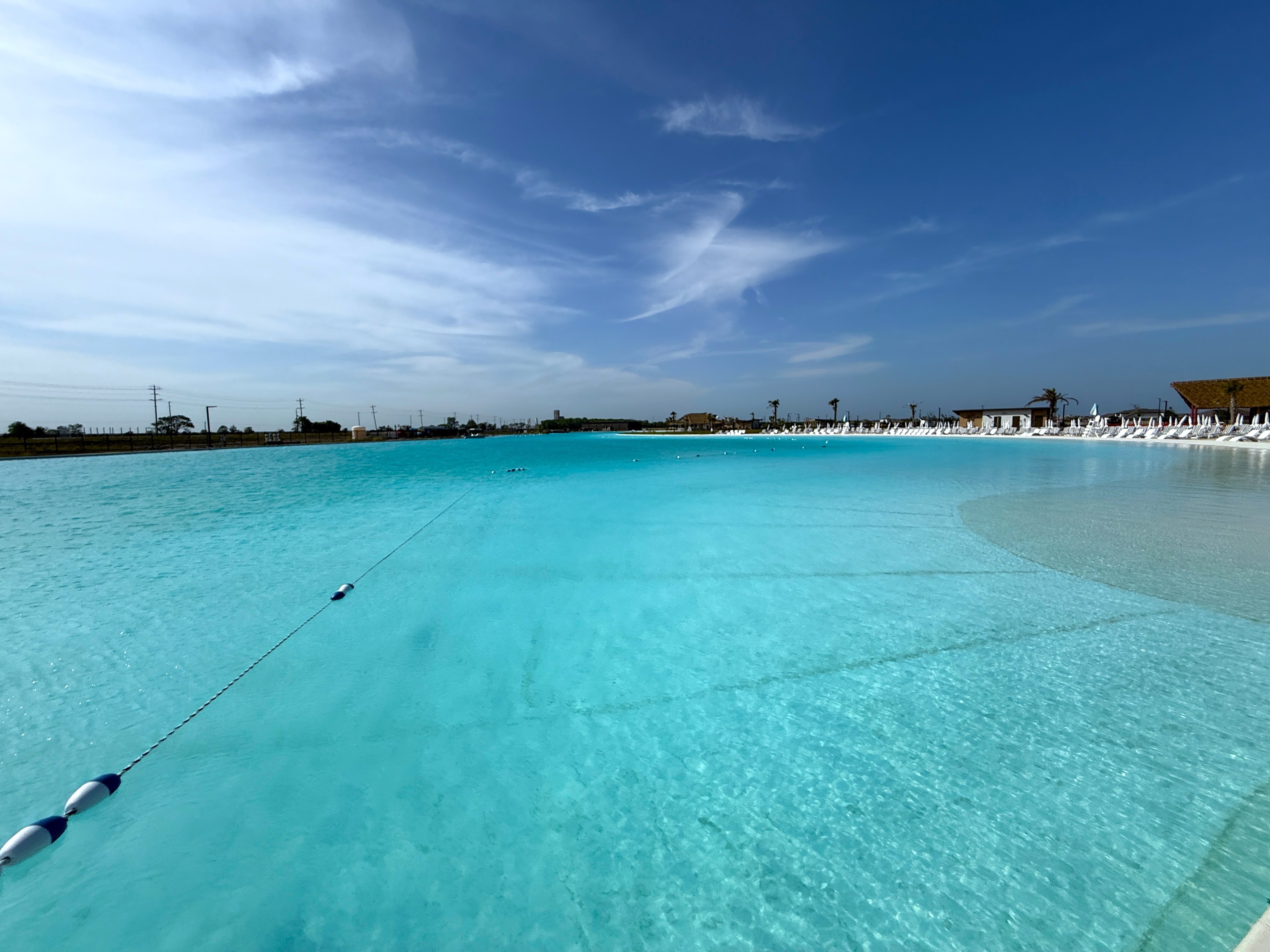 Turquoise Lagoon at River Ranch Community Crystal-clear lagoon with sandy shore, lounge chairs, and palm trees, River Ranch community, under a clear blue sky.