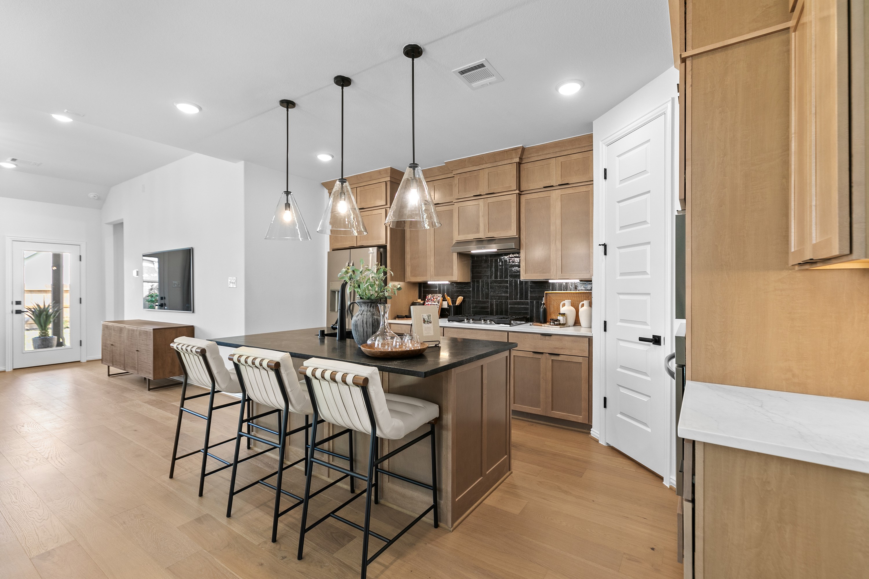 River Ranch Modern Kitchen with Wood Cabinets and Black Island Modern kitchen in River Ranch with wood cabinets, black island, pendant lights, and door to patio.