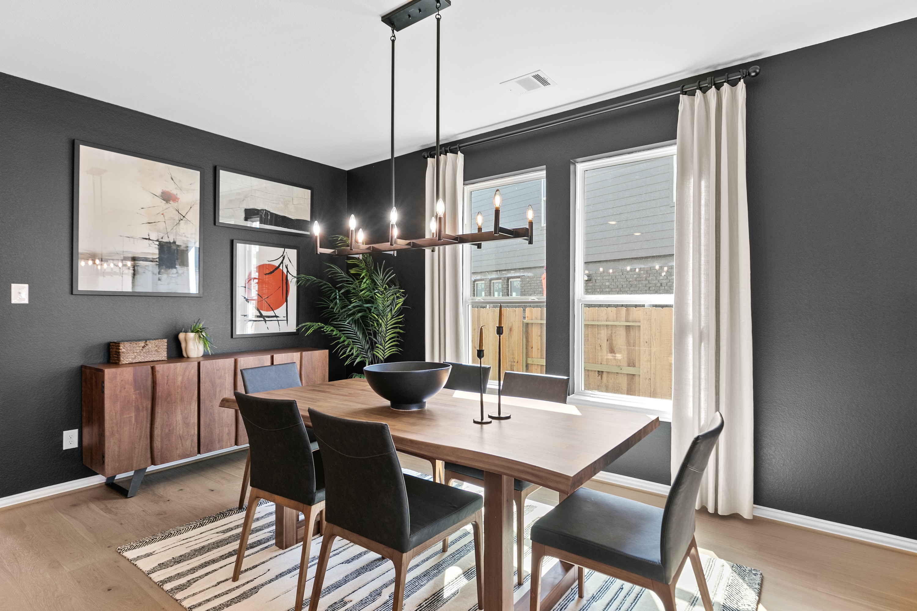 Luxurious Dining Room with Modern Flair in River Ranch Elegant dining room, dark accent wall, modern chandelier, large windows, wood table in River Ranch.