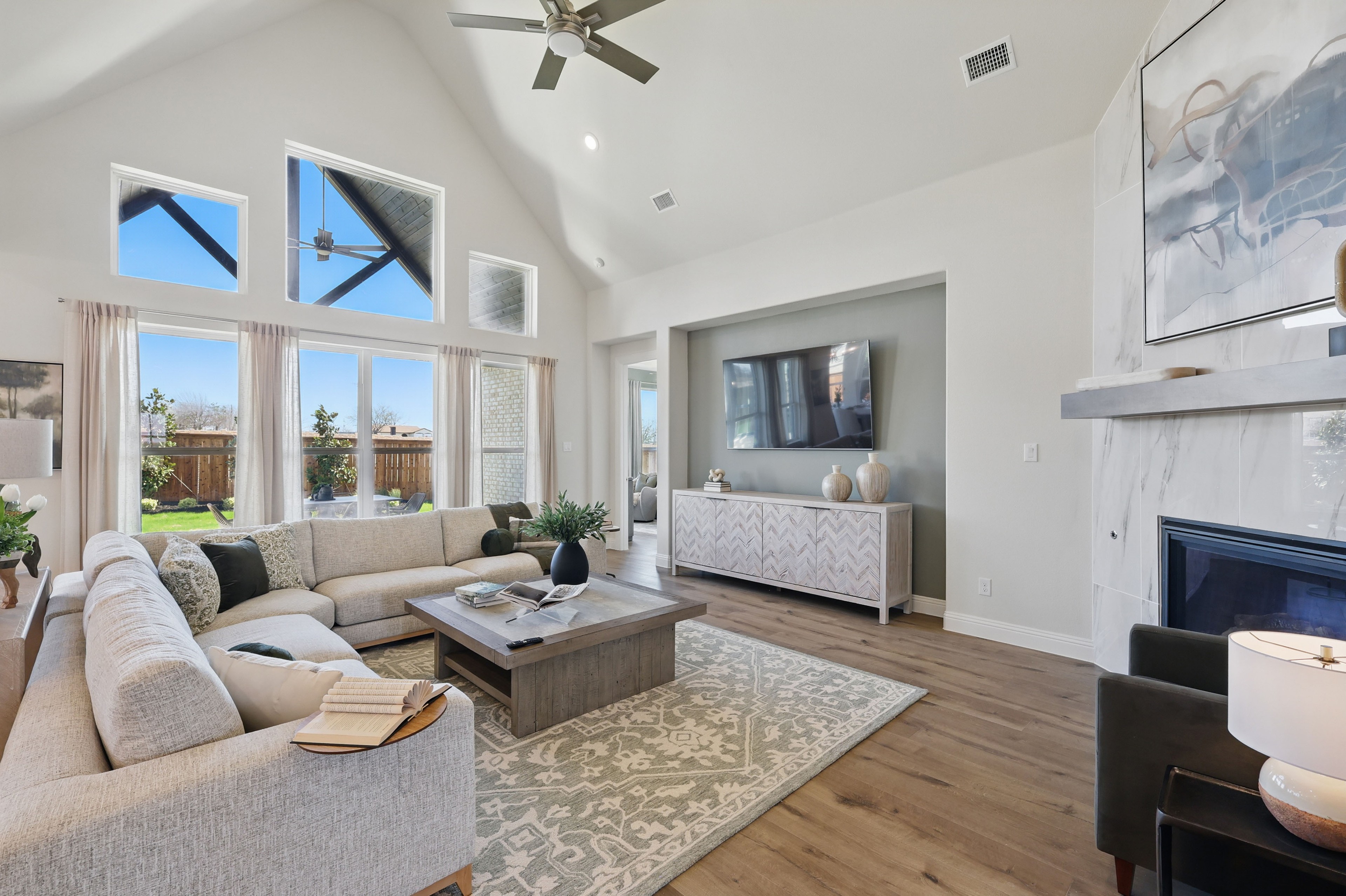 Modern Living Room with Vaulted Ceilings in Rio Vista at Kelly Ranch Spacious living room with vaulted ceiling, modern decor, large windows, elegant fireplace, Rio Vista at Kelly Ranch.