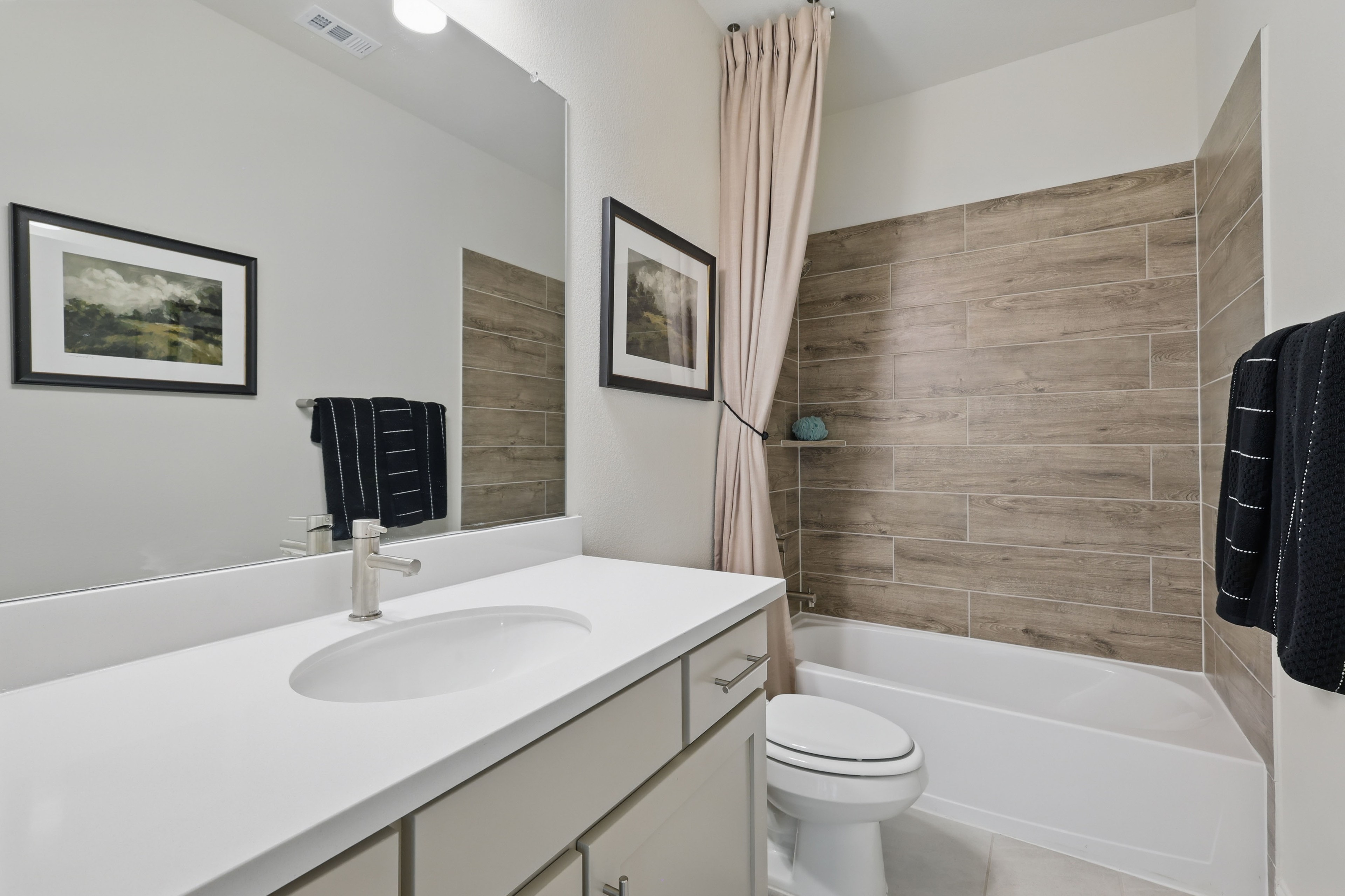 Elegant Bathroom with Wood Tiles at Rio Vista, Kelly Ranch Modern bathroom with wood-patterned tiles, white vanity, and mounted artwork at Rio Vista, Kelly Ranch.