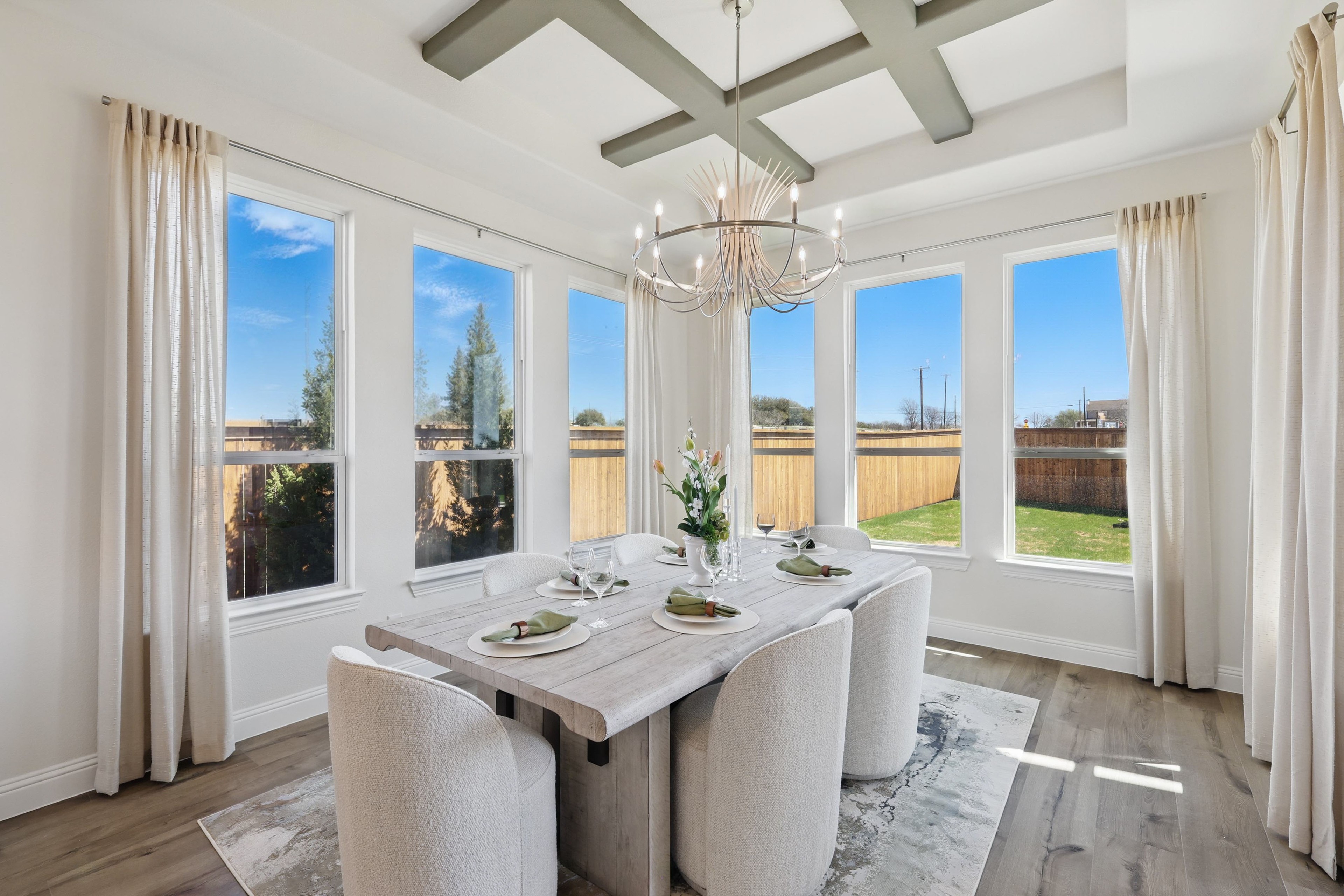 Elegant Dining Room in Rio Vista at Kelly Ranch Elegant dining room with chandelier, large windows, and coffered ceiling in Rio Vista at Kelly Ranch.