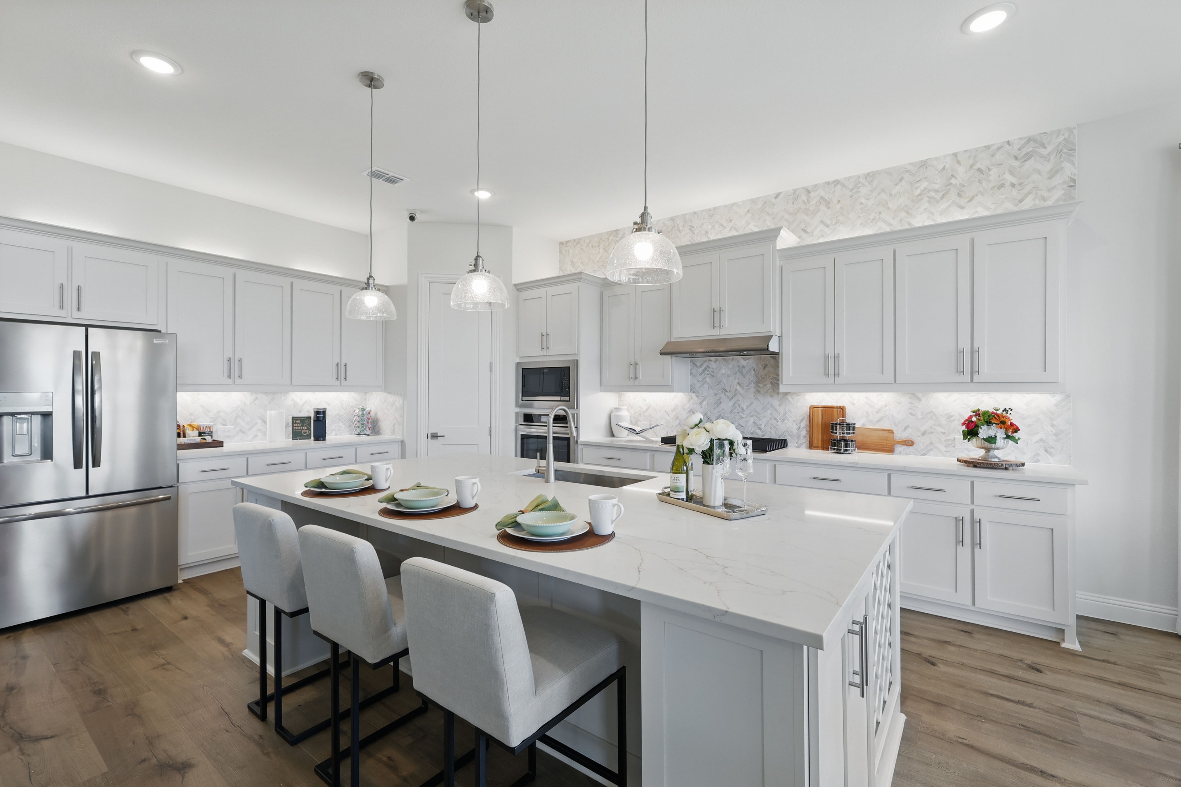 Elegant White Cabinet Kitchen in Rio Vista at Kelly Ranch Modern kitchen with white cabinets, marble island, pendant lights in Rio Vista at Kelly Ranch, hardwood floor.