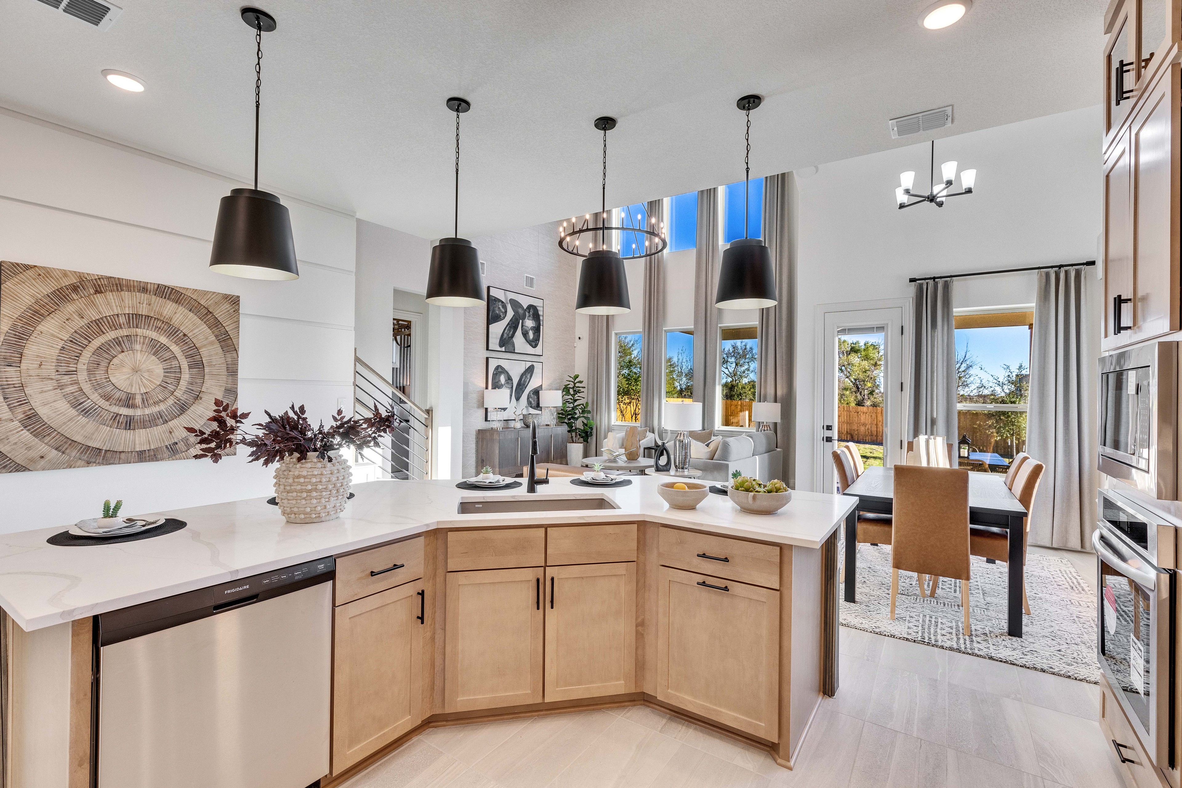 Modern Kitchen and Living Area in Creeks Crossing Community Modern kitchen with pendant lights, wood cabinets, and open living area in Creeks Crossing community.
