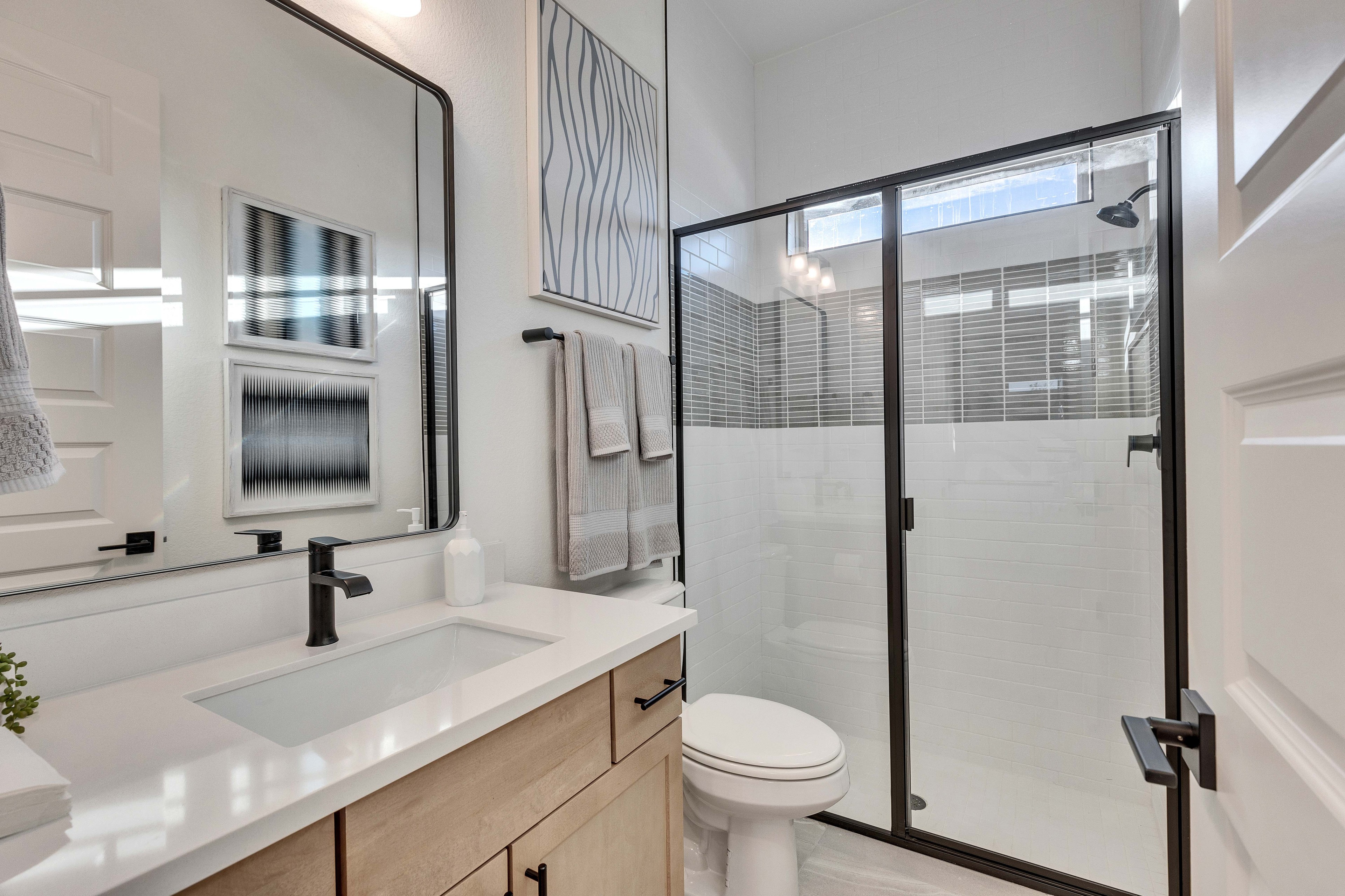 Modern Bathroom with Sleek Shower and Vanity in Creeks Crossing Modern bathroom in Creeks Crossing with sleek shower, black fixtures, and elegant wood vanity.