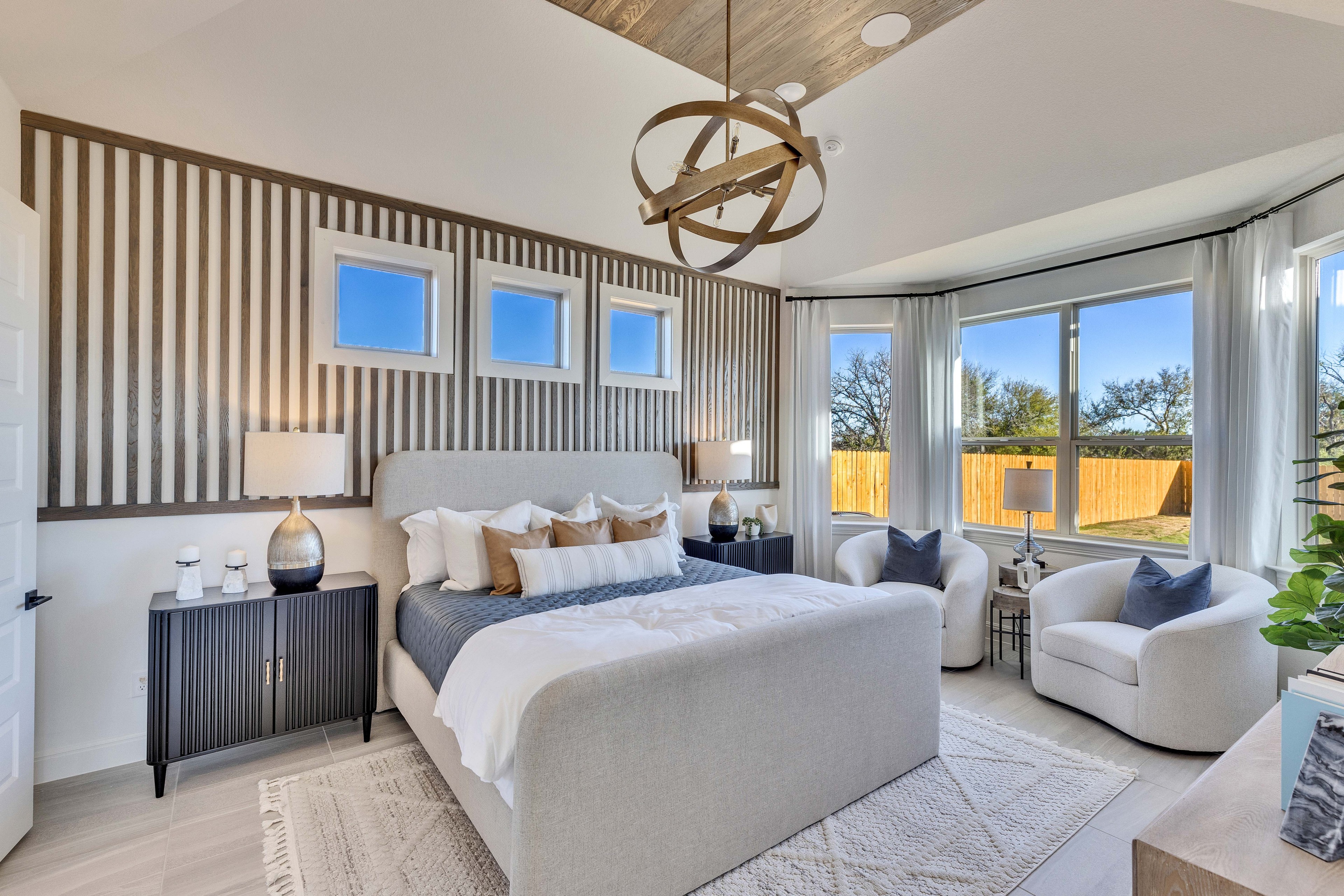 Elegant Bedroom Design in Creeks Crossing with Modern Décor Luxurious Creeks Crossing bedroom with wood accent wall, modern lighting, and large windows with scenic views.