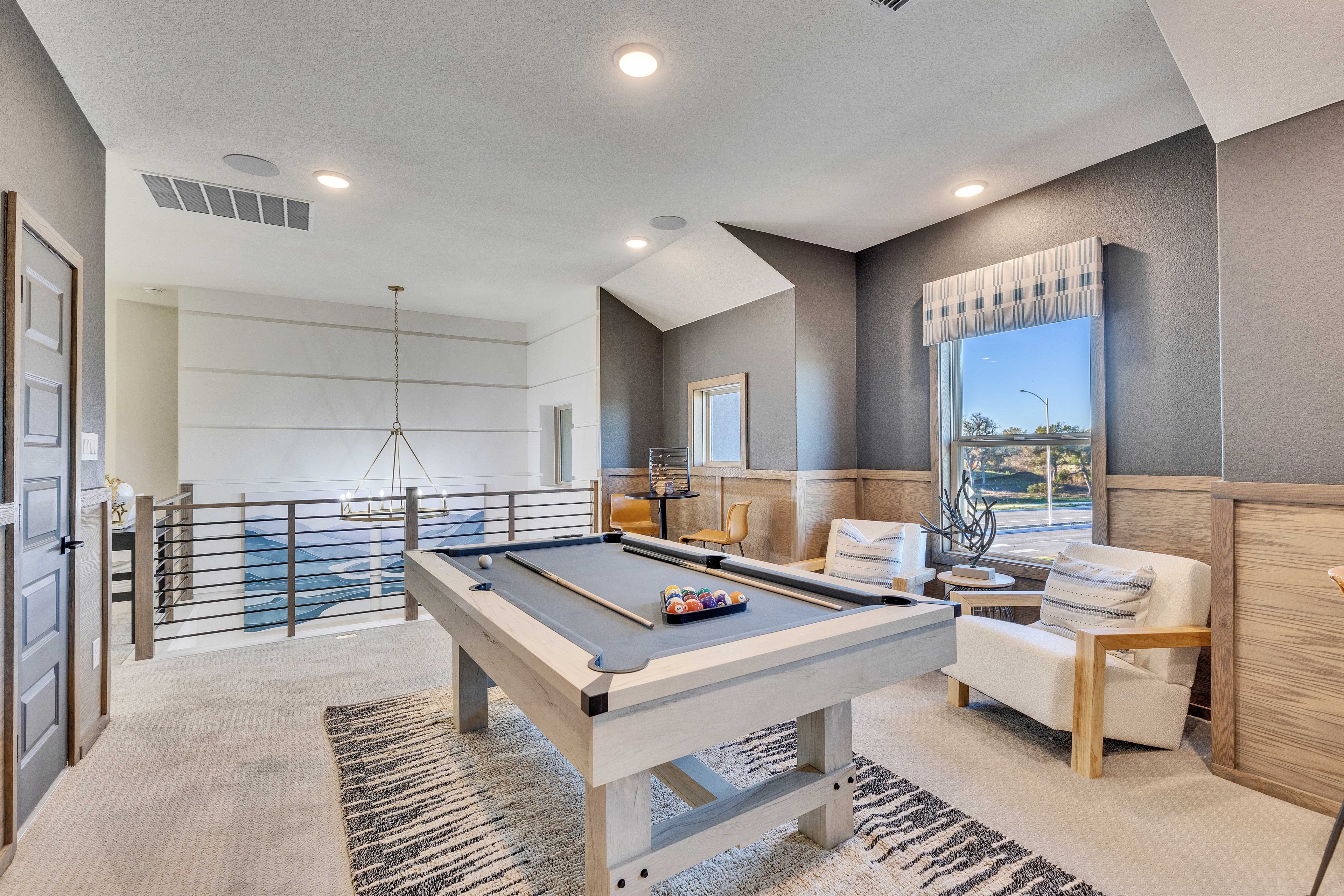 Luxurious Game Room with Pool Table in Creeks Crossing Luxurious game room with modern pool table, plush chairs, large window, elegant chandelier, Creeks Crossing.