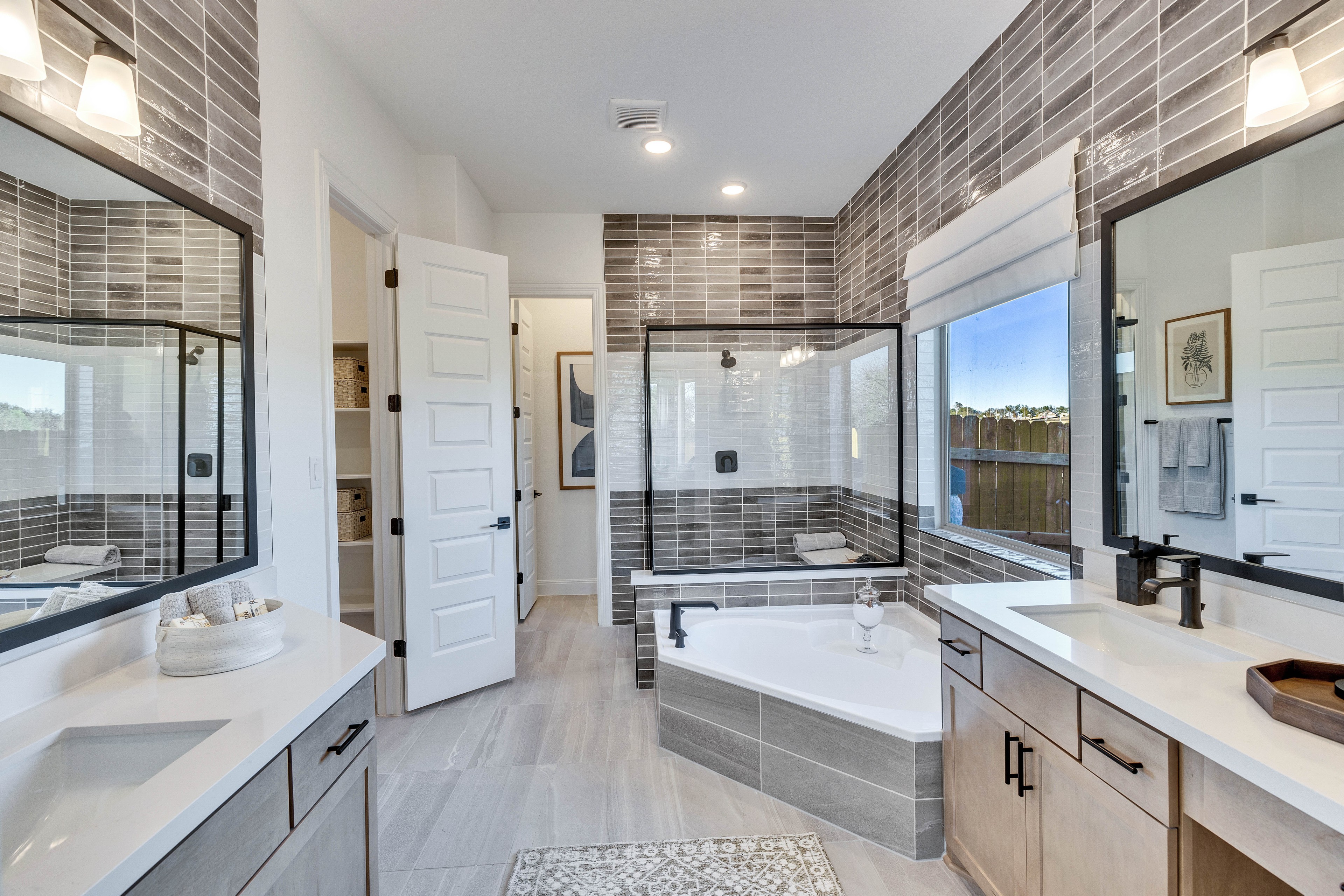 Luxury Bathroom with Tiled Walls and Tub in Creeks Crossing Luxurious bathroom with gray tiled walls, soaking tub, and walk-in shower in Creeks Crossing community.