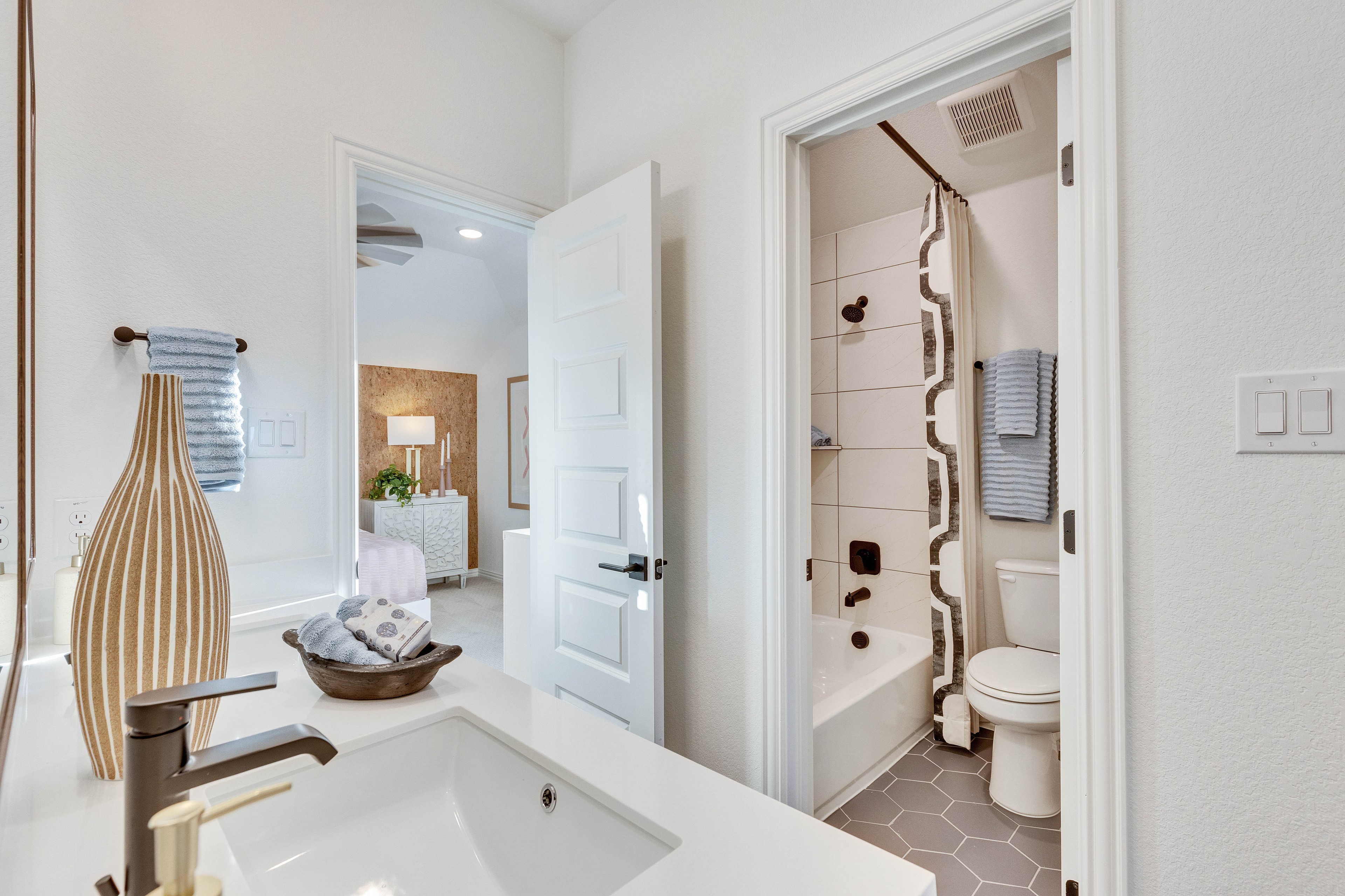 Luxury Bathroom with Modern Finishes in Creeks Crossing Modern bathroom with sleek white sink, decorative vase, and hexagonal tiles in Creeks Crossing.