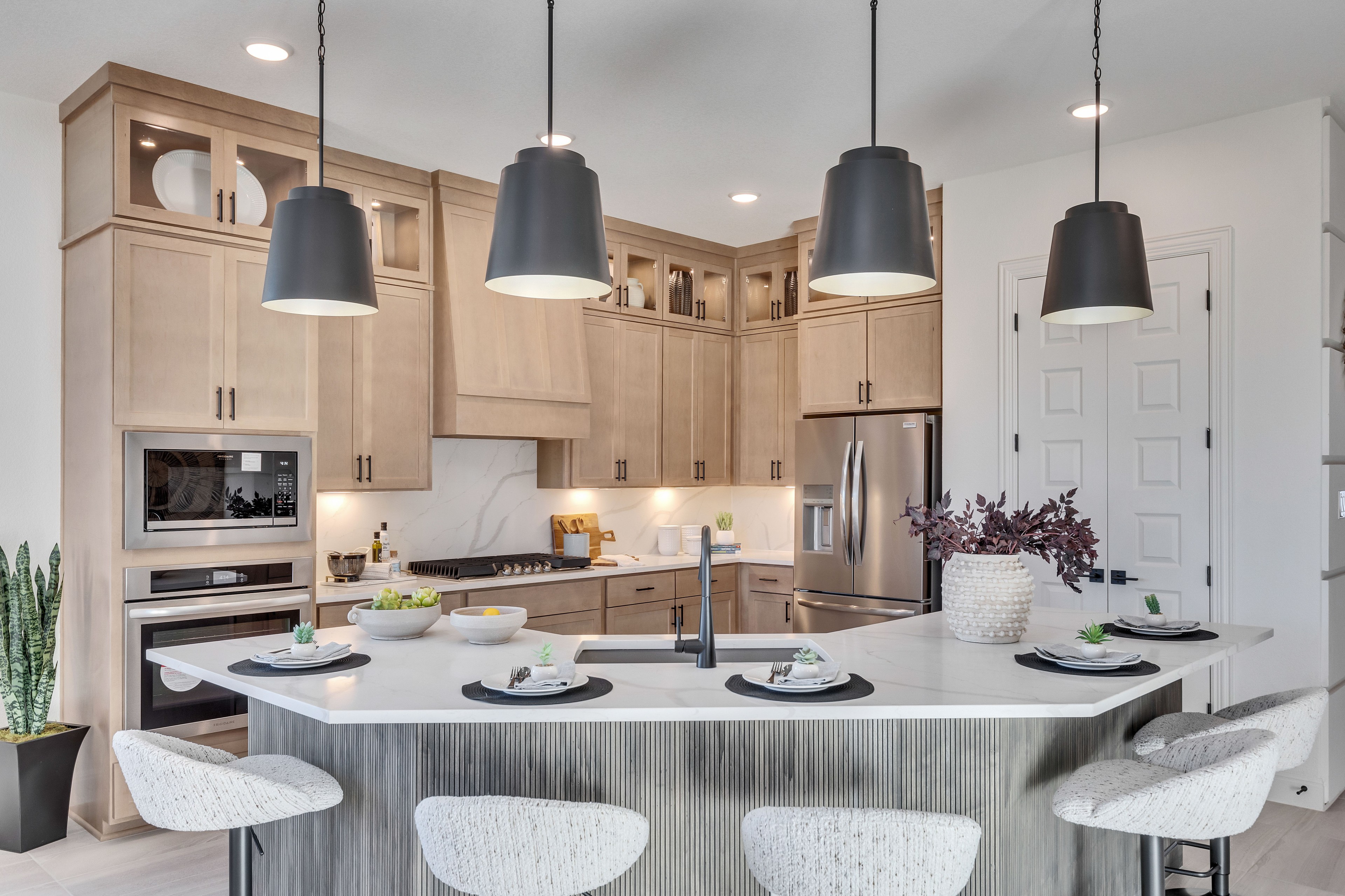 Luxury Kitchen with Marble Countertops in Creeks Crossing Modern kitchen with marble countertops, hanging lights, and wooden cabinets in Creeks Crossing community.