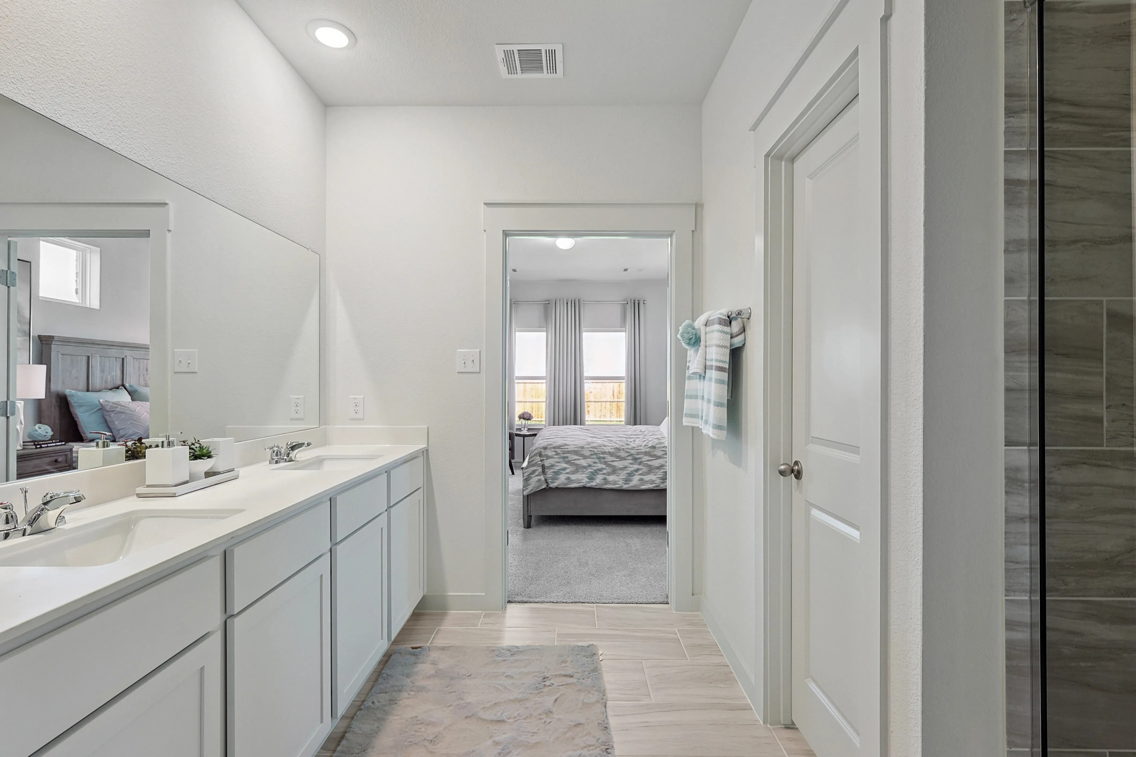 Modern Bathroom with Double Sinks in Patriot Estates Residence Spacious modern bathroom with double sinks, large mirror, neutral tones in Patriot Estates home visible through doorway.