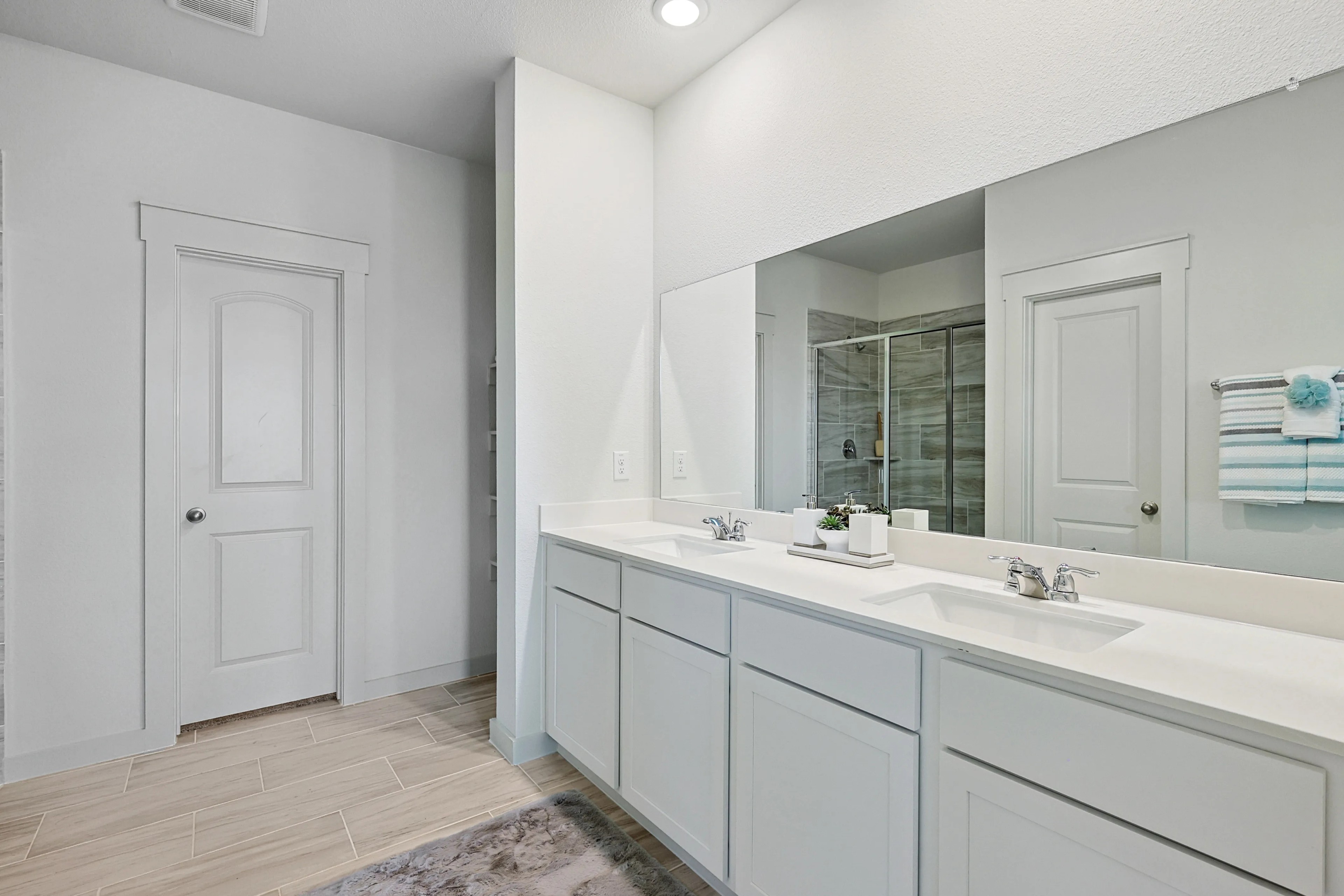 Patriot Estates Bathroom With Dual Vanities and Modern Decor Modern bathroom in Patriot Estates with dual sink vanity, large mirror, glass shower, and wood tile flooring.