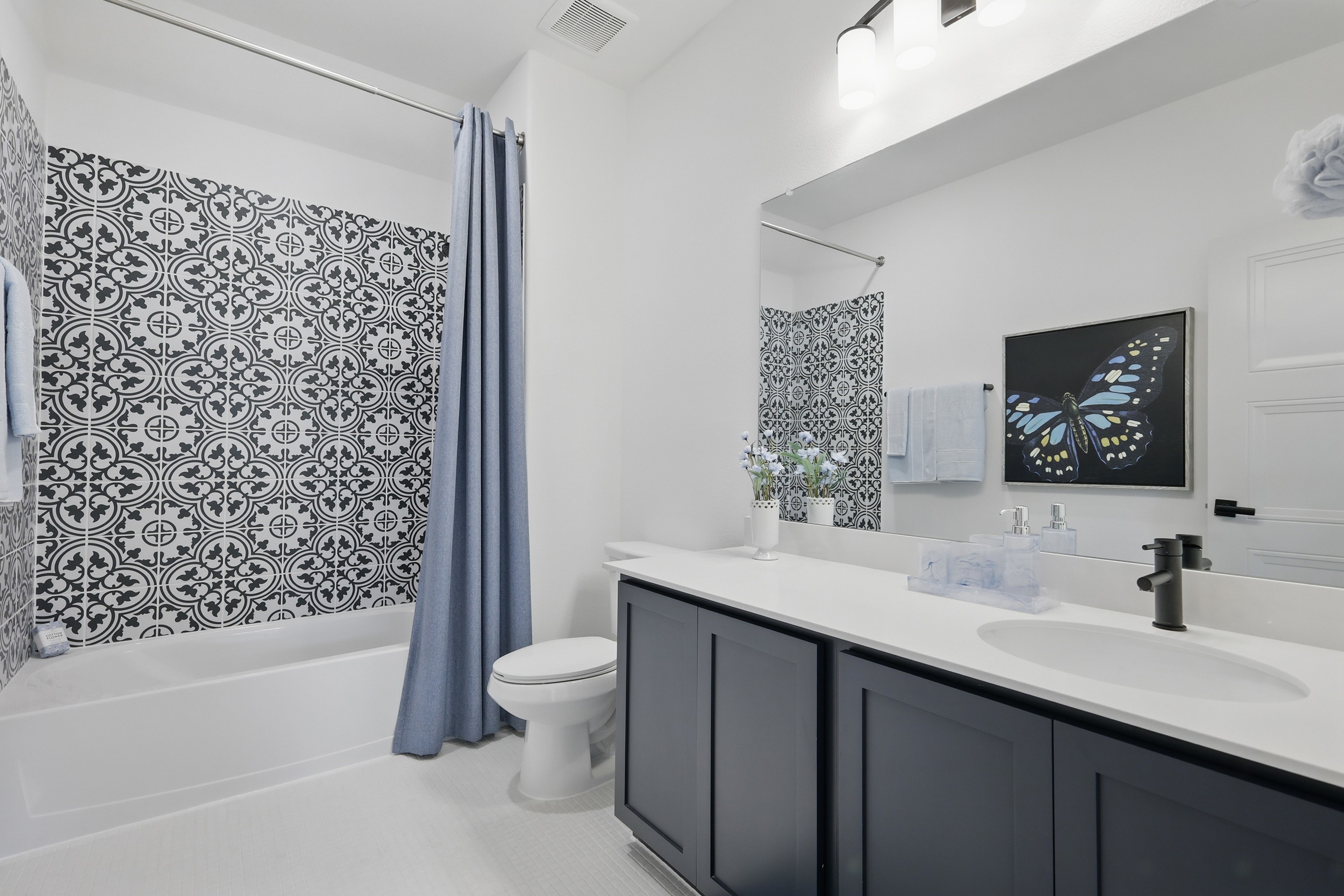 Elegant Black Vanity Bathroom with Patterned Tiles in Westridge Modern bathroom with patterned tile, black vanity, and blue accents in Westridge community.