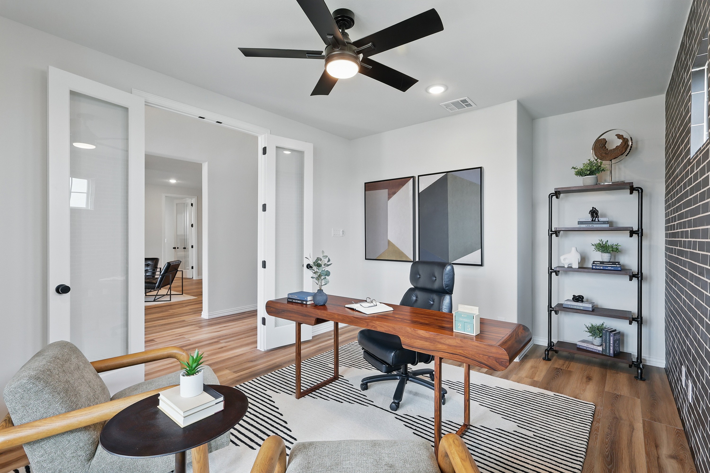 Modern Home Office Design in Westridge Community Modern home office with wood desk, art, glass doors, and black fan in Westridge community.