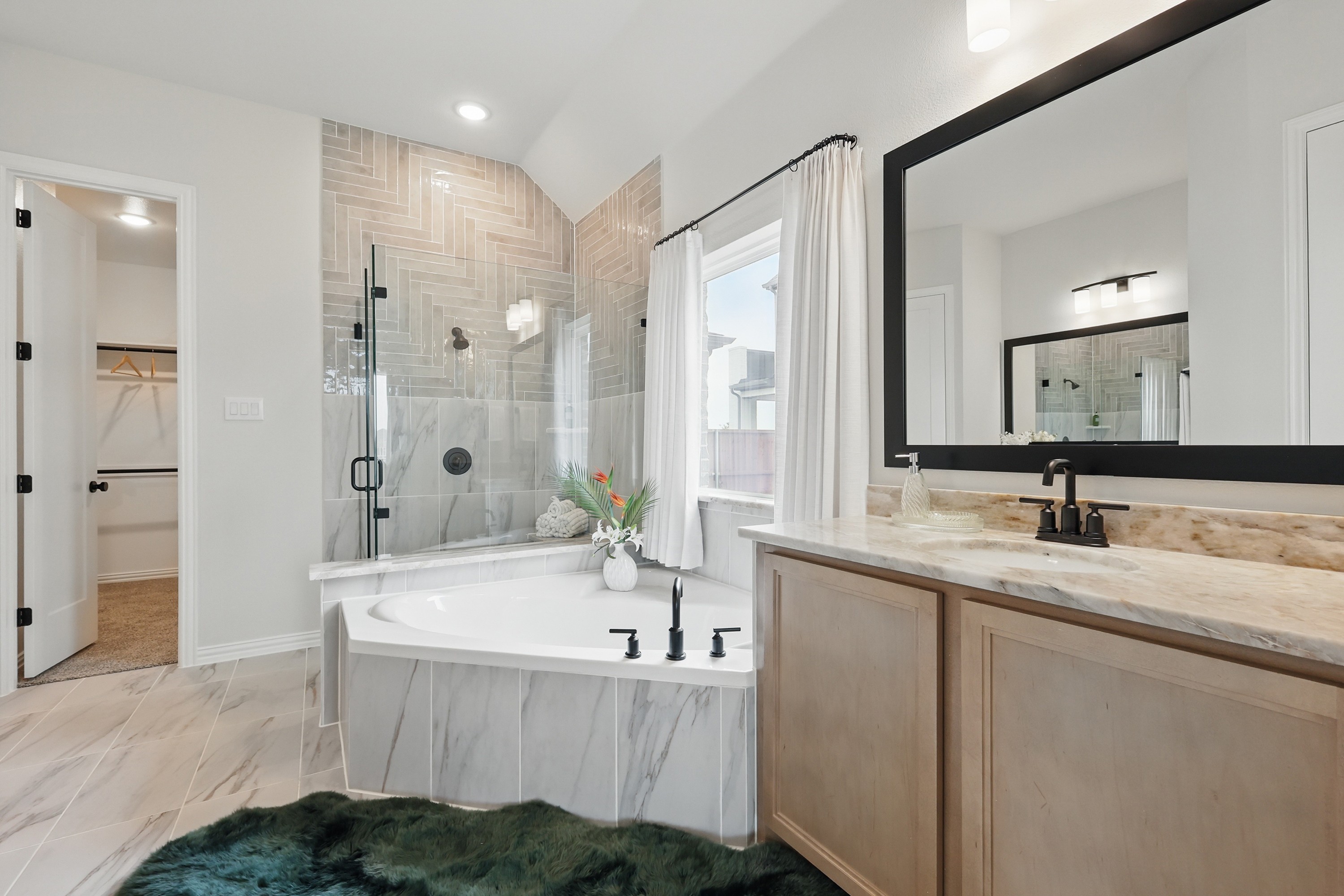 Elegant Marble Bathroom with Glass Shower in Westridge Community Luxurious bathroom with marble tub, glass shower, tiled walls, and large mirror in Westridge community.