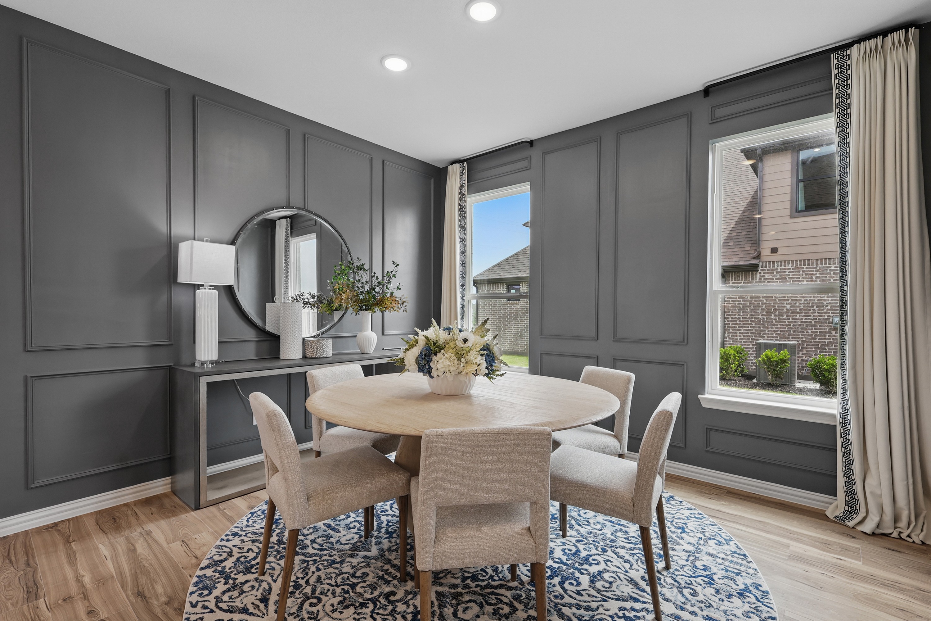 Elegant Dining Room in Westridge Community with Modern Gray Paneling Chic dining area with round table, gray paneled walls, and large windows in Westridge community.