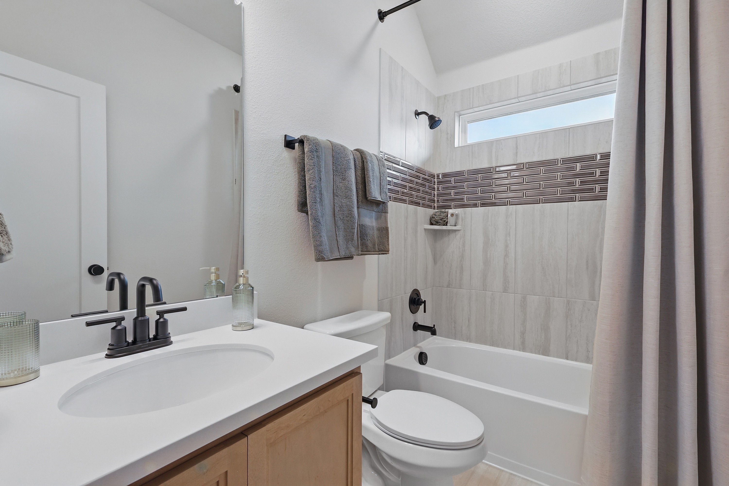 Elegant Modern Bathroom with Marble Tiles in Westridge Elegant bathroom with modern fixtures, marble tiles, and accent wall in Westridge community.