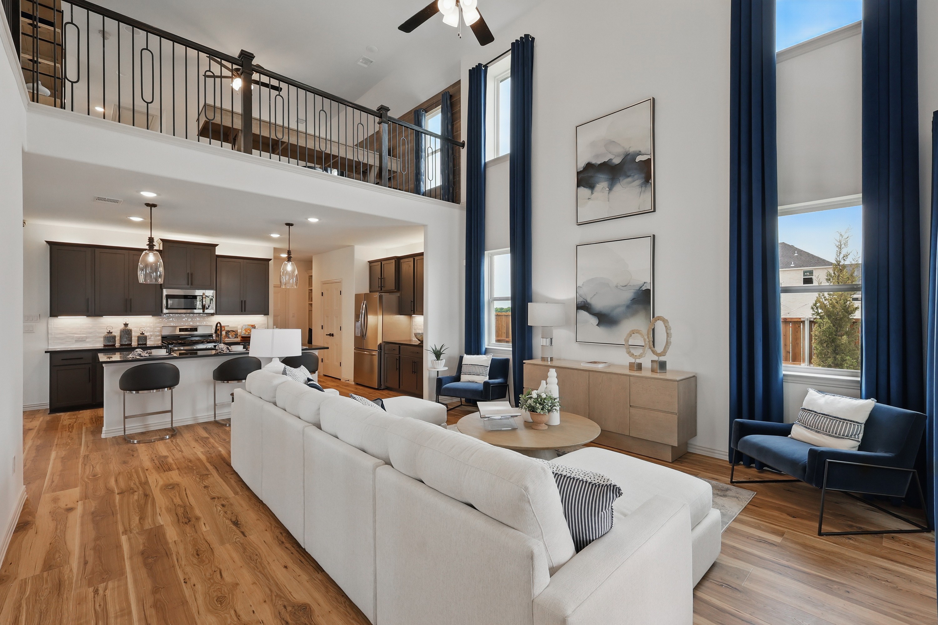 Open-concept living room with balcony and high ceiling in Westridge Modern open-concept living area with high ceiling, wood floors, and balcony in Westridge community home.