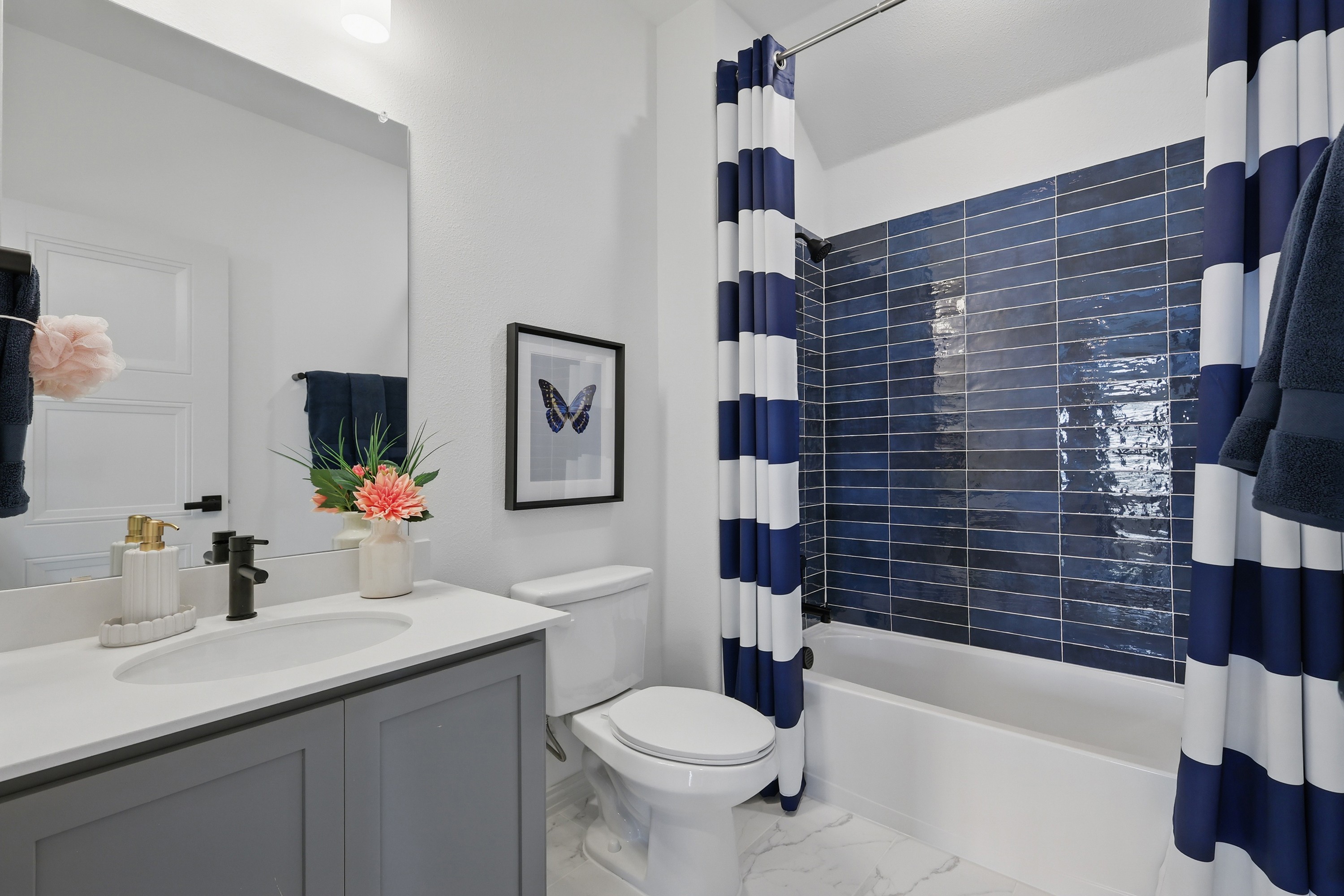 Contemporary Bathroom Design in Westridge Community Modern bathroom with navy tiles, striped shower curtain, elegant vanity, Westridge community.