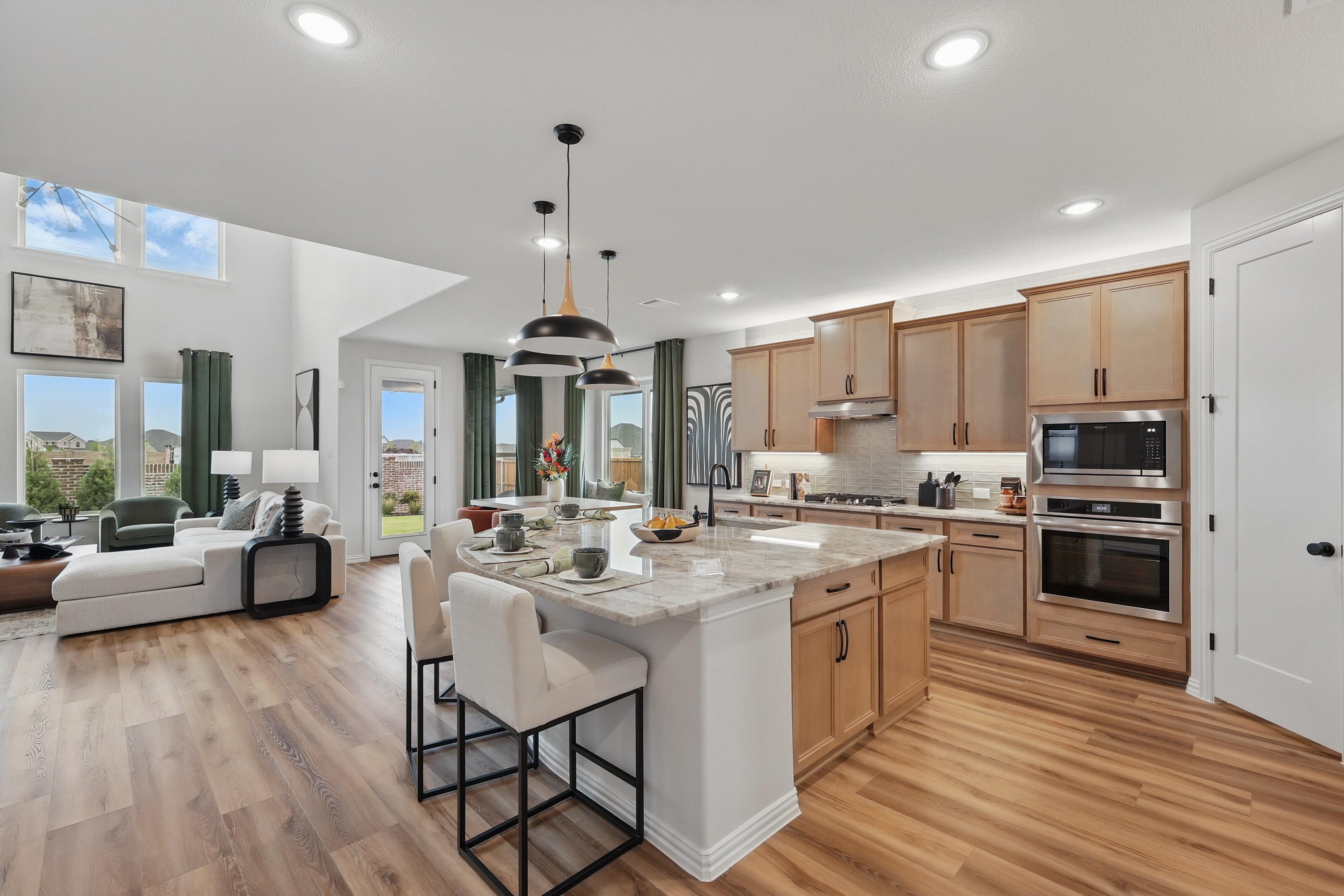 Modern Kitchen and Living Area in Westridge Community Open-plan kitchen and living area with wood cabinets, island, modern lighting, in Westridge community.