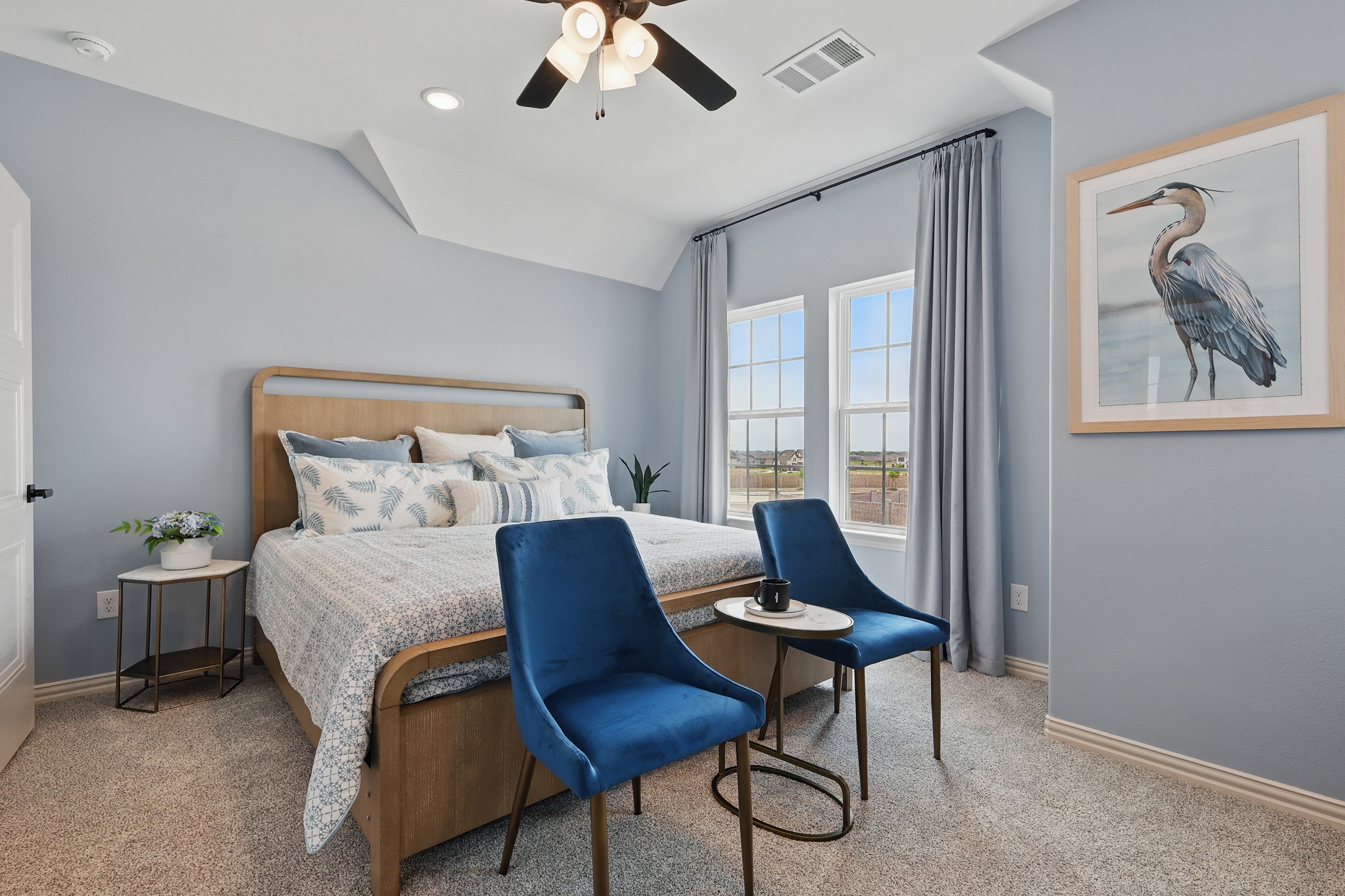 Stylish Bedroom in Westridge with Velvet Chairs and Heron Art Elegant Westridge bedroom with blue velvet chairs, wooden bed, heron art, and large windows offering natural light.