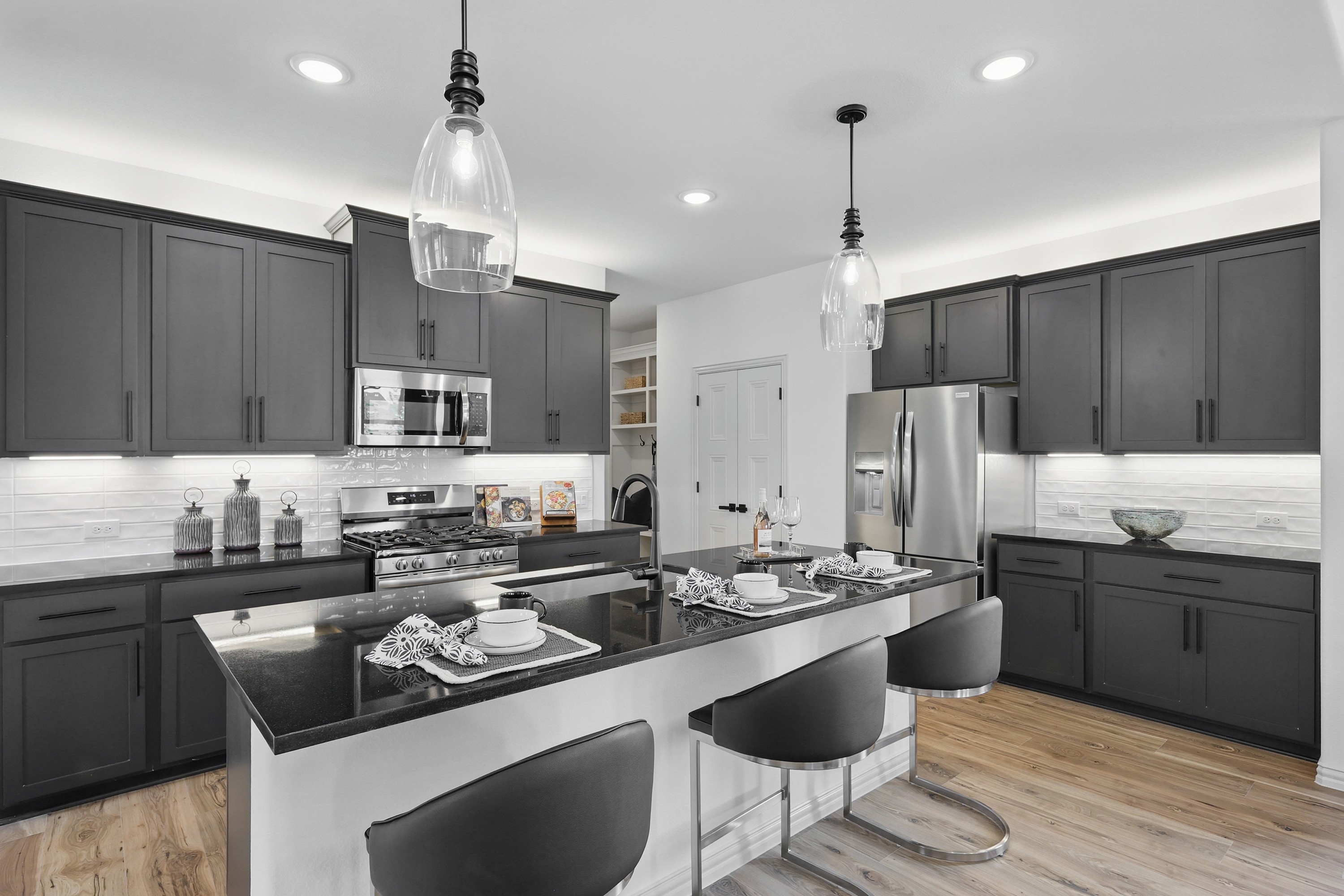 Elegant Modern Kitchen in Westridge with Dark Cabinets and Island Modern kitchen with dark cabinets, stainless steel appliances, pendant lights, Westridge.