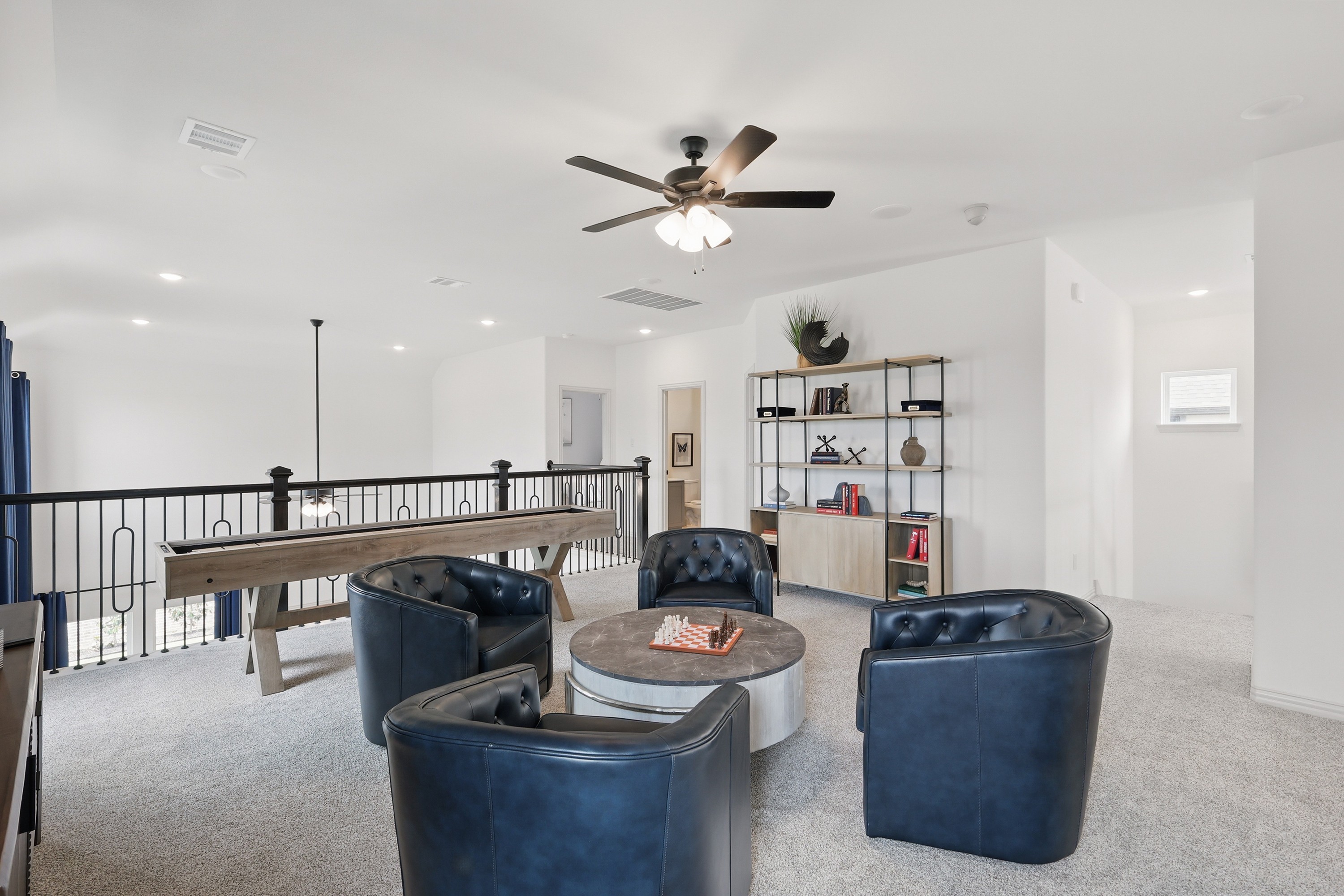 Contemporary Loft with Blue Chairs and Railing, Westridge Texas Modern loft with plush blue chairs, sleek black railing, ceiling fan, bookshelf, Westridge, Texas.