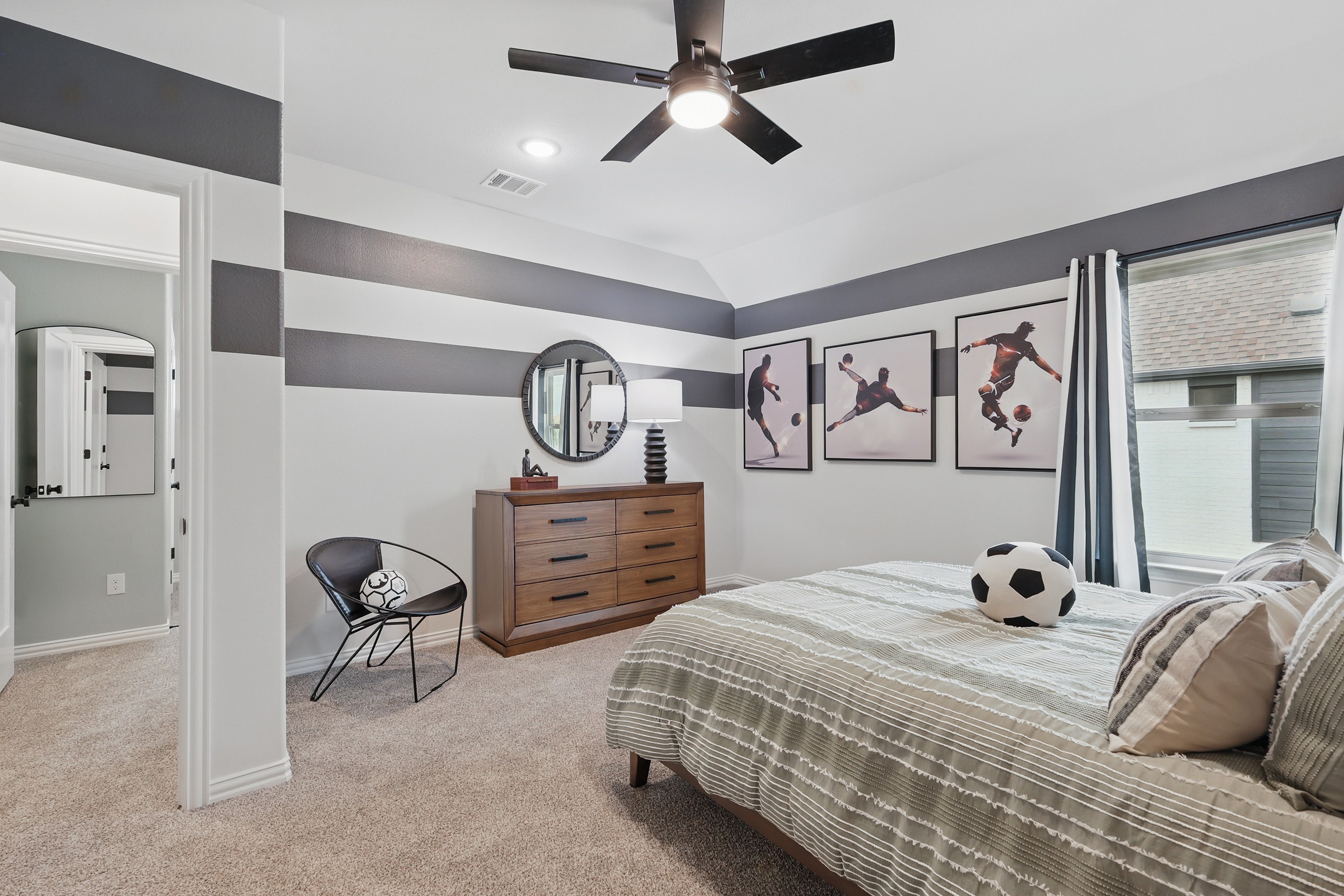 Elegant Modern Bedroom with Sports Decor in Westridge Community Modern bedroom with striped walls, sports decor, and ceiling fan in Westridge community. Neutral tones add elegance.
