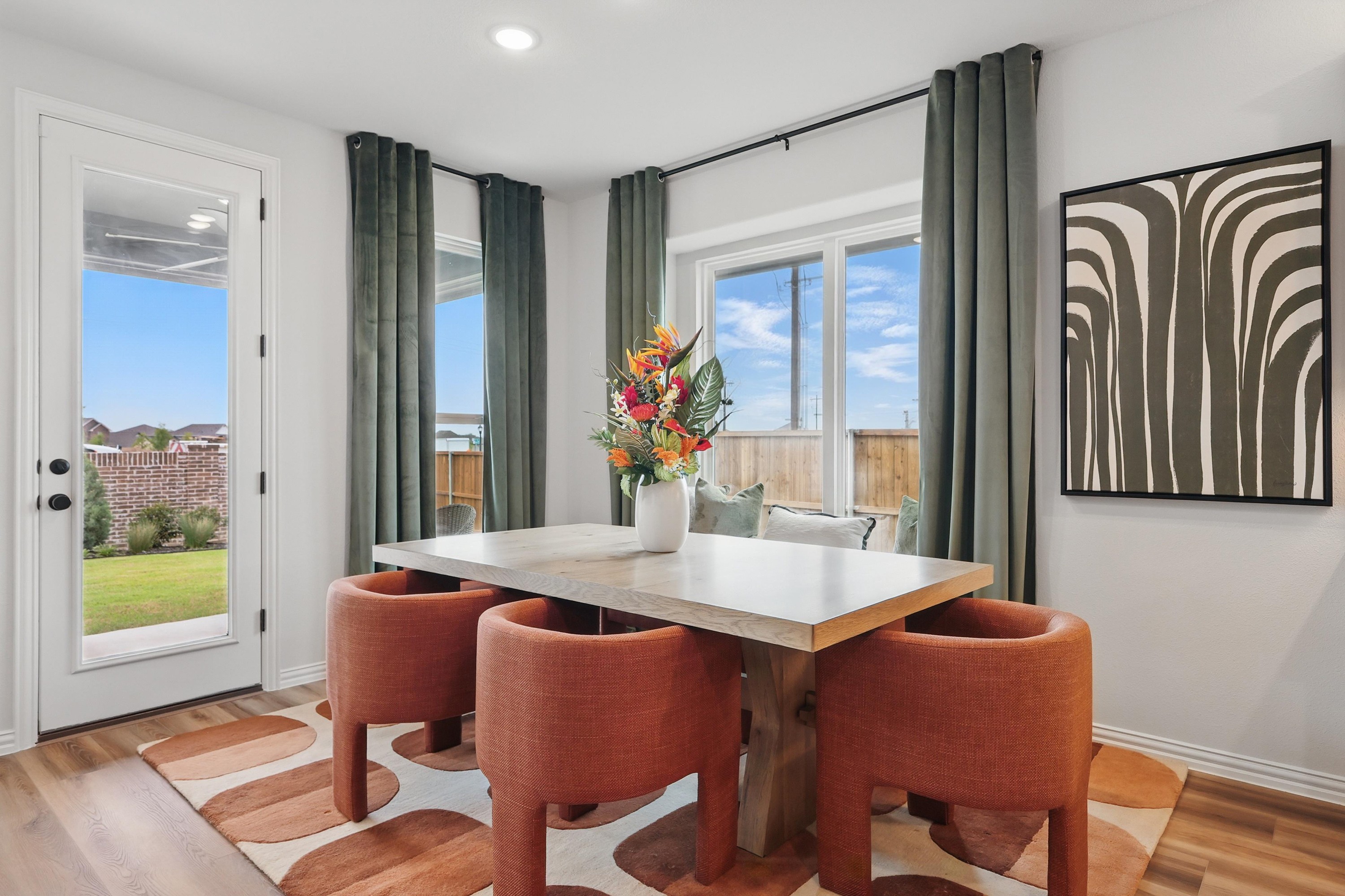 Elegant Dining Area with Garden View in Westridge Community Dining nook with modern table, orange chairs, art piece, and garden patio view in Westridge community.